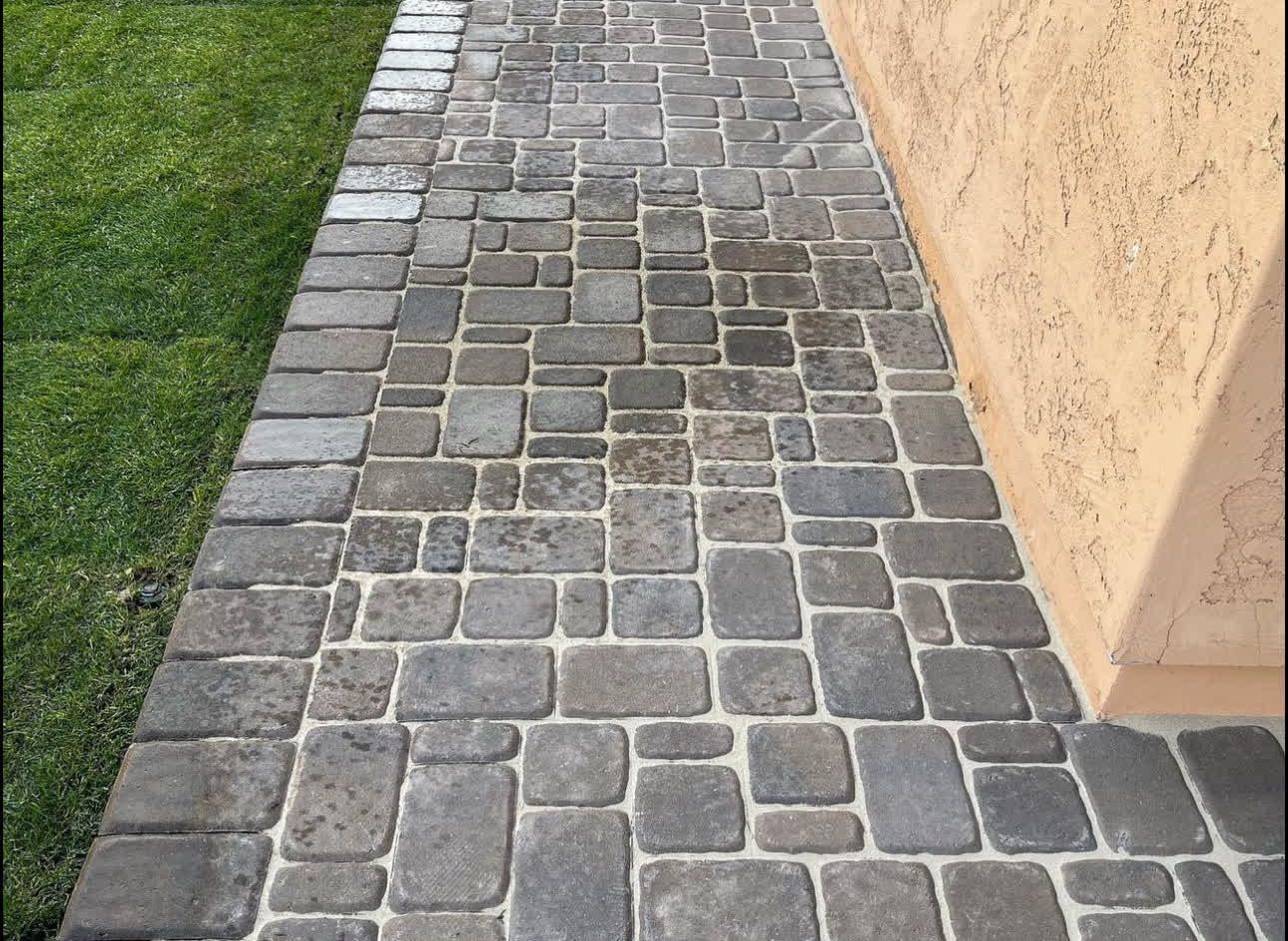 A sidewalk made of bricks is next to a building.