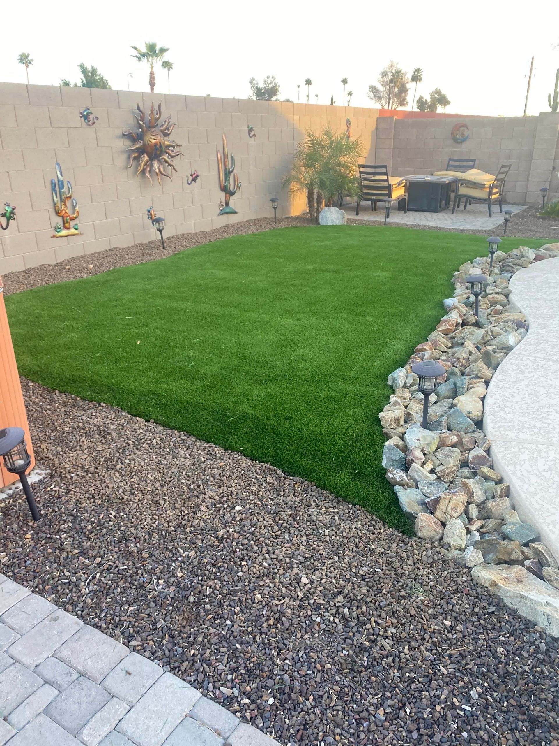A backyard with a lush green lawn and a brick walkway.