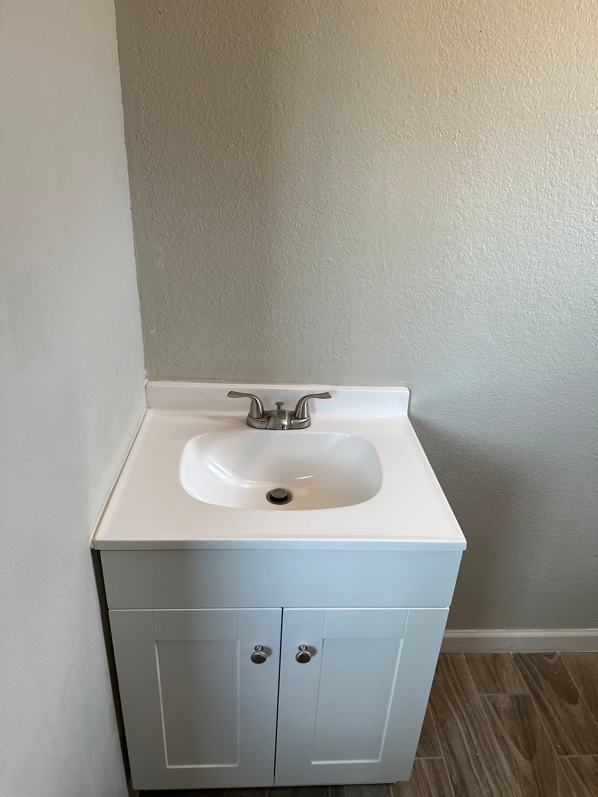 A bathroom sink with a white cabinet and a silver faucet.