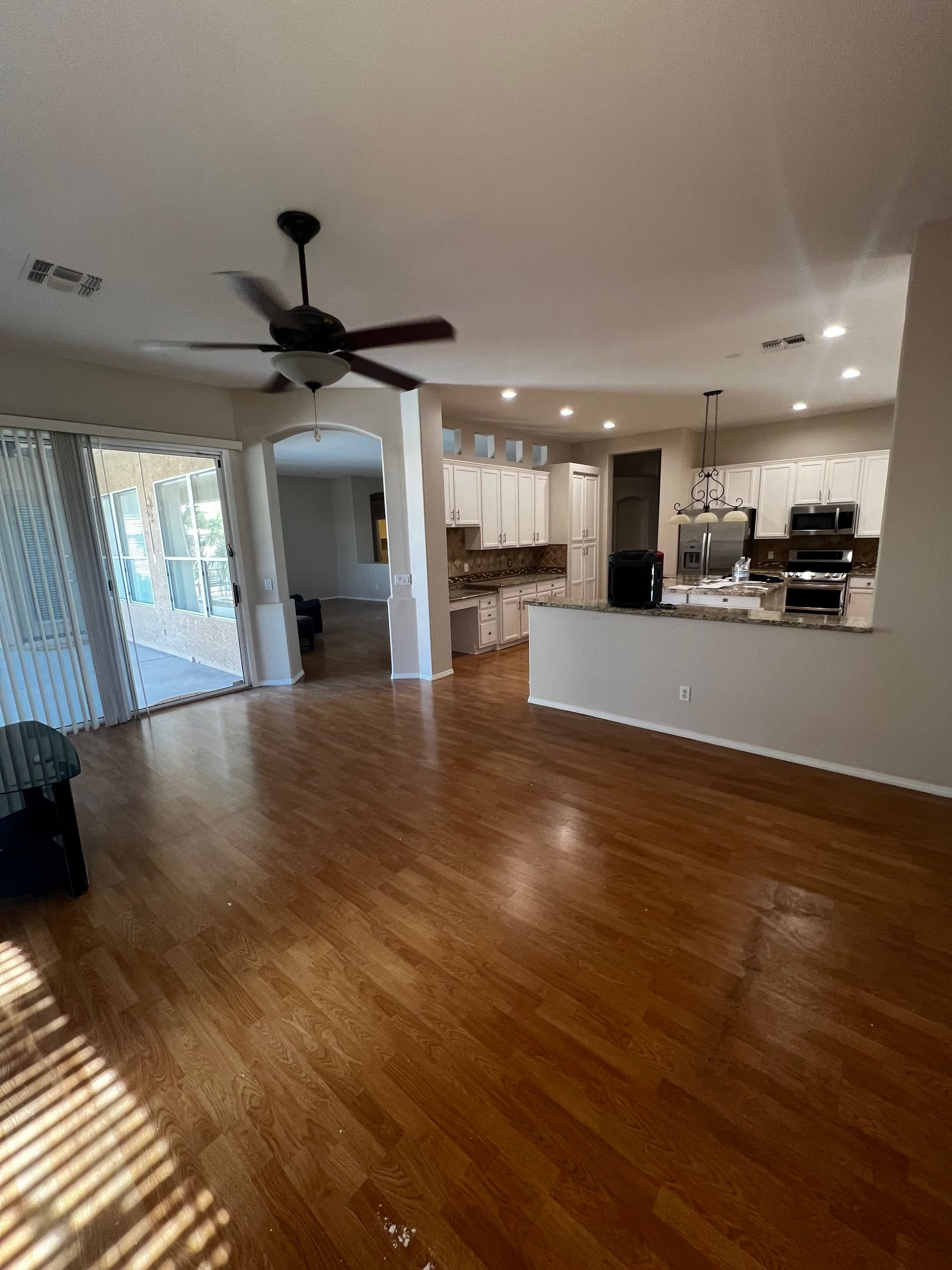 A living room with hardwood floors and a ceiling fan.