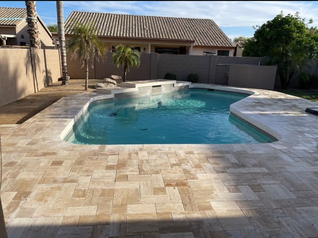 A large swimming pool in a backyard with a house in the background