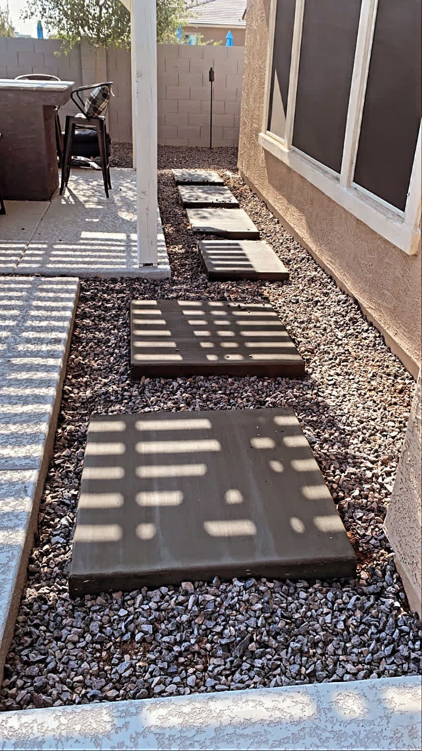 A row of concrete walkways leading to a patio in a backyard.