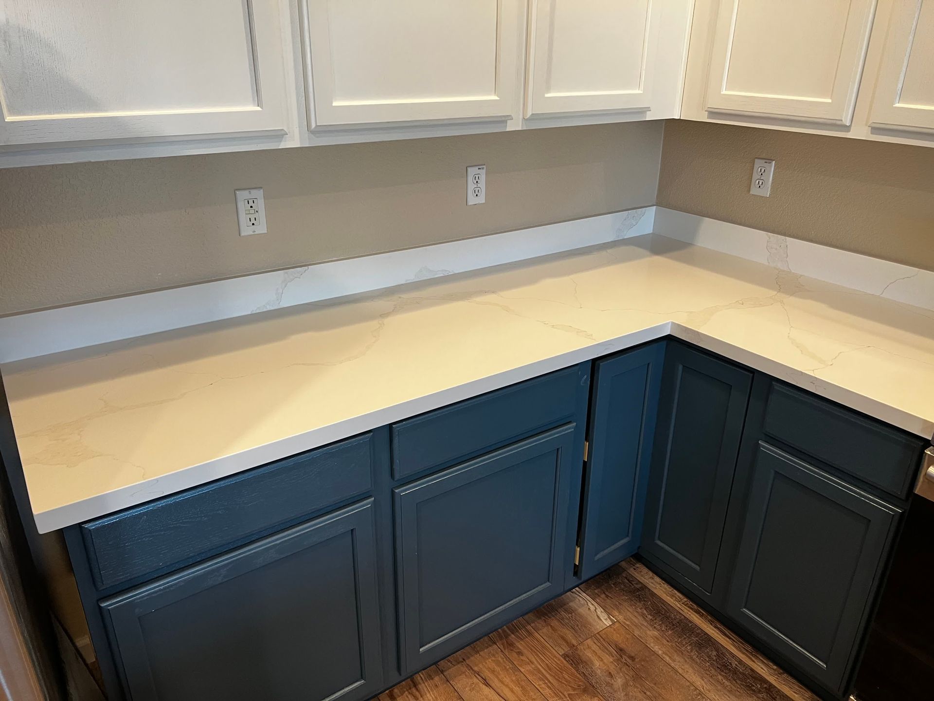 A kitchen with blue cabinets and white counter tops.