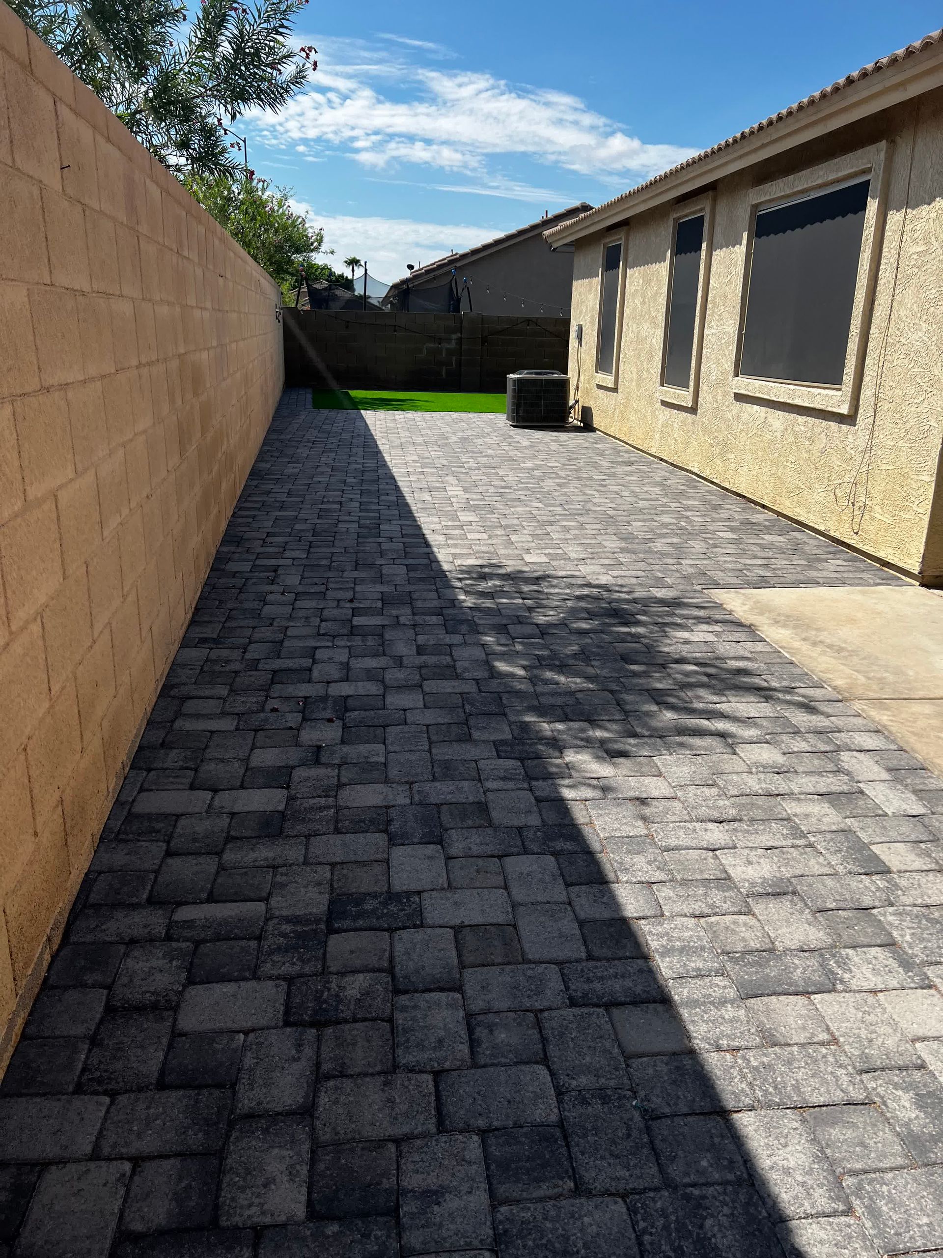 A brick walkway leading to a house with a brick wall.