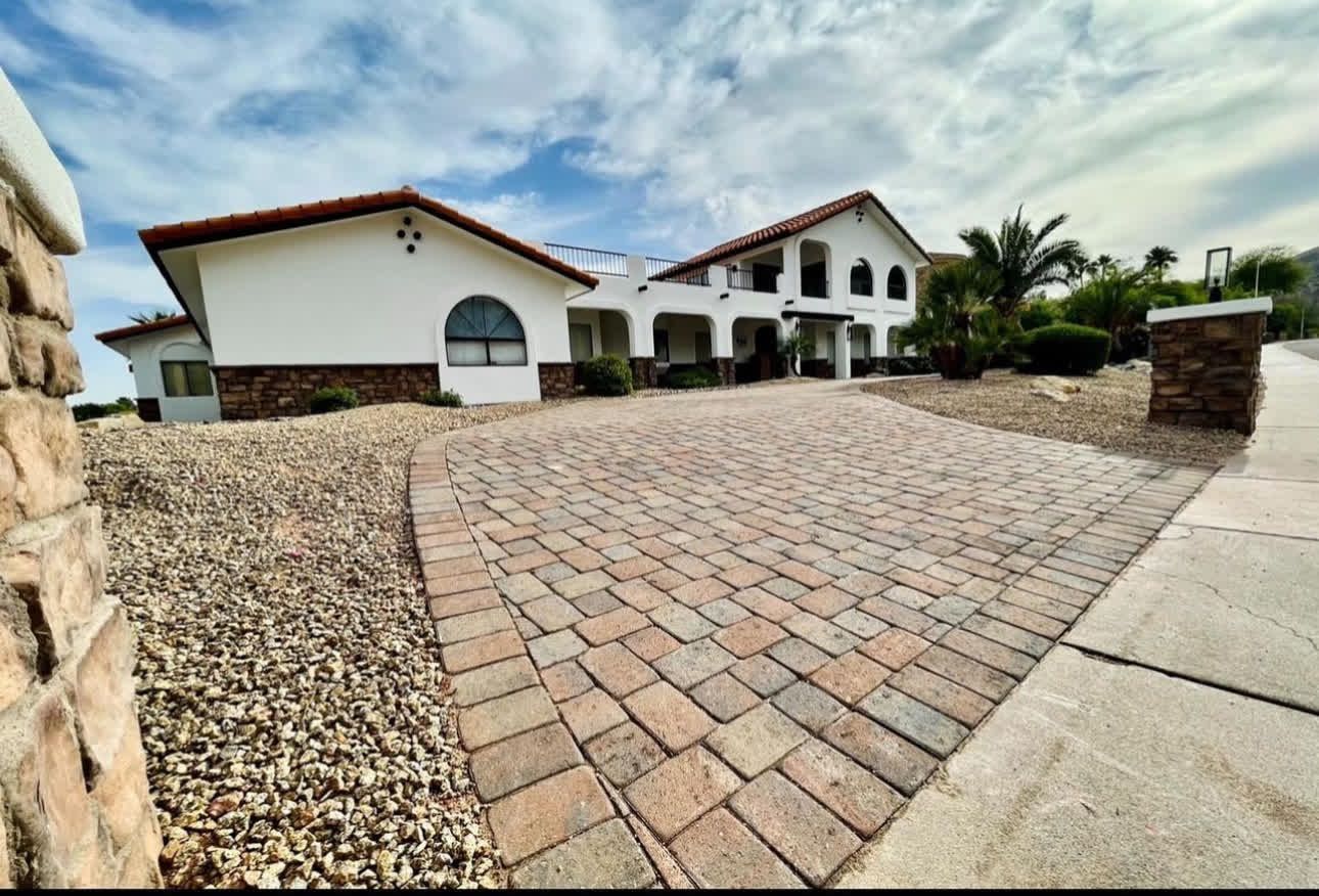 A large white house with a brick driveway in front of it
