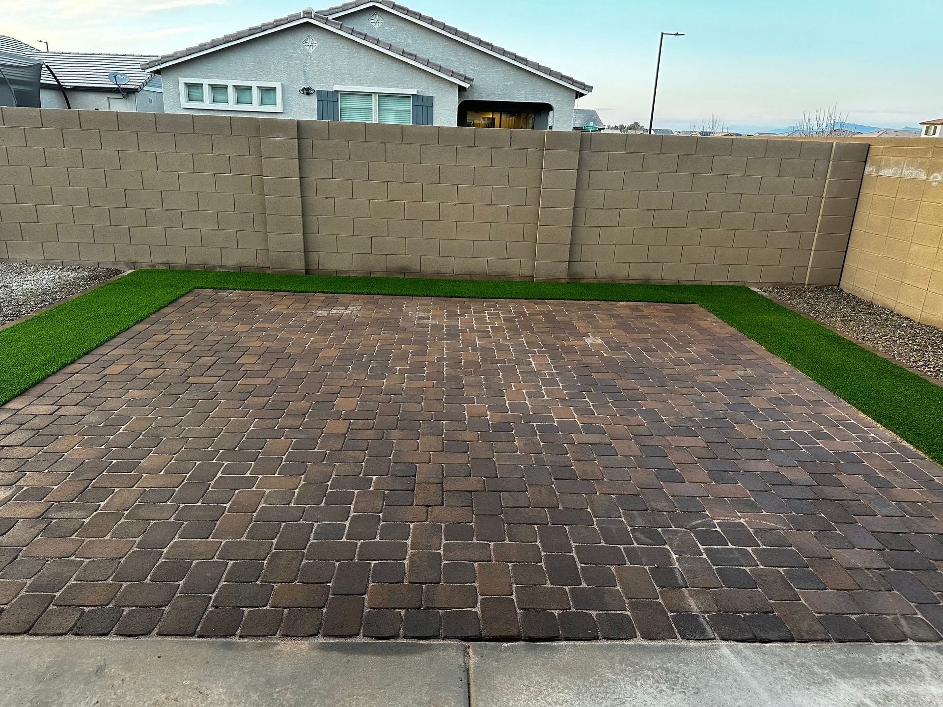 A brick driveway with a house in the background