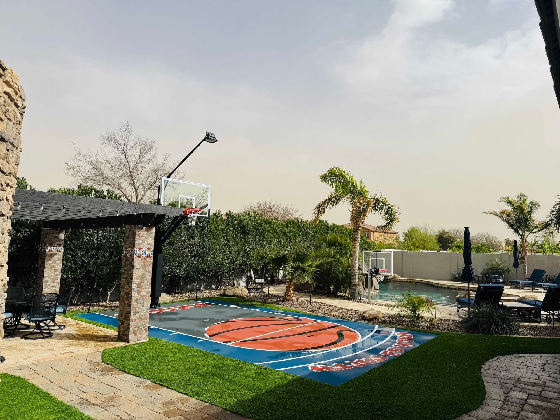There is a basketball court in the backyard of a house.