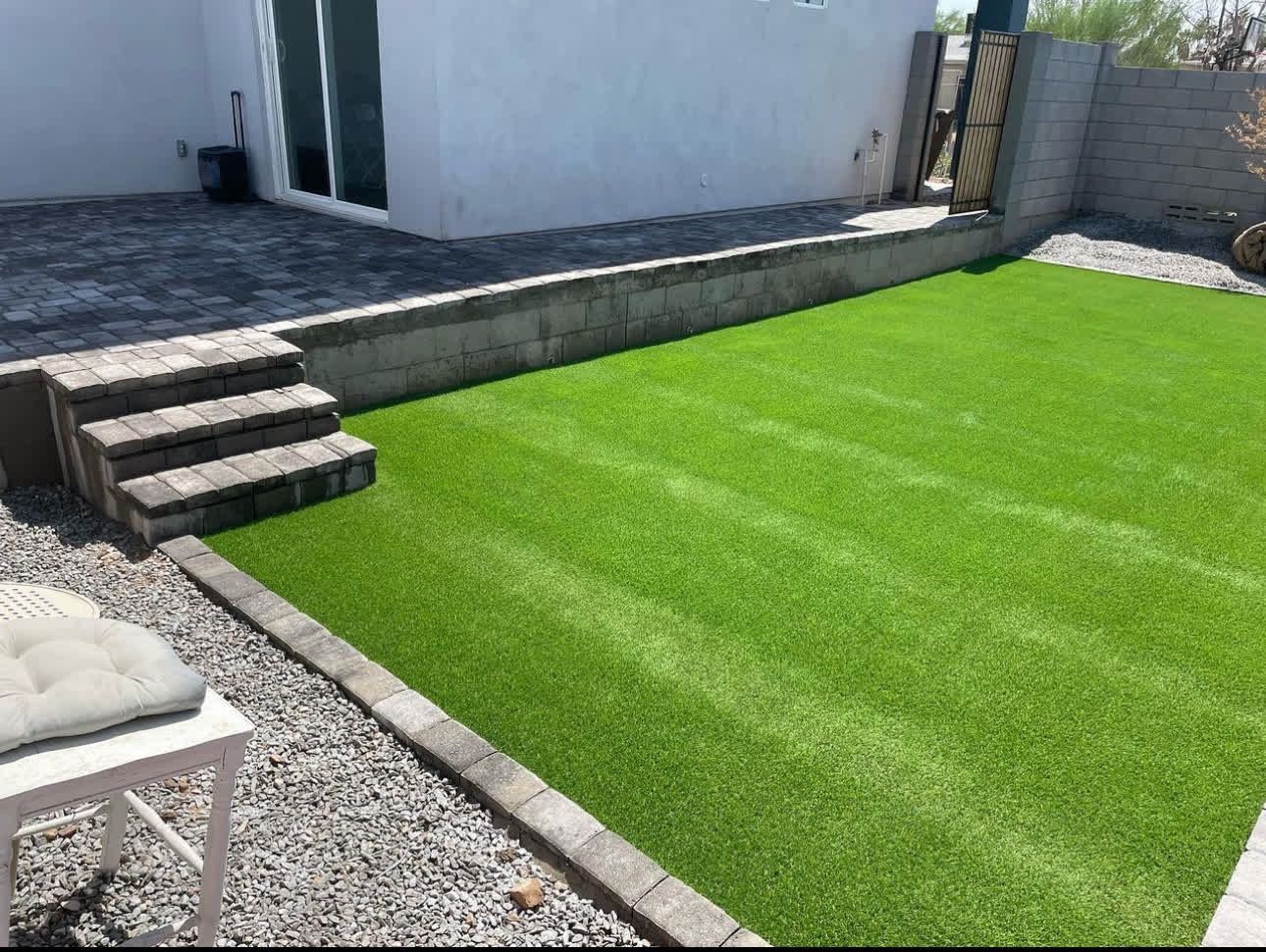 A backyard with a lush green lawn and stairs leading up to it.