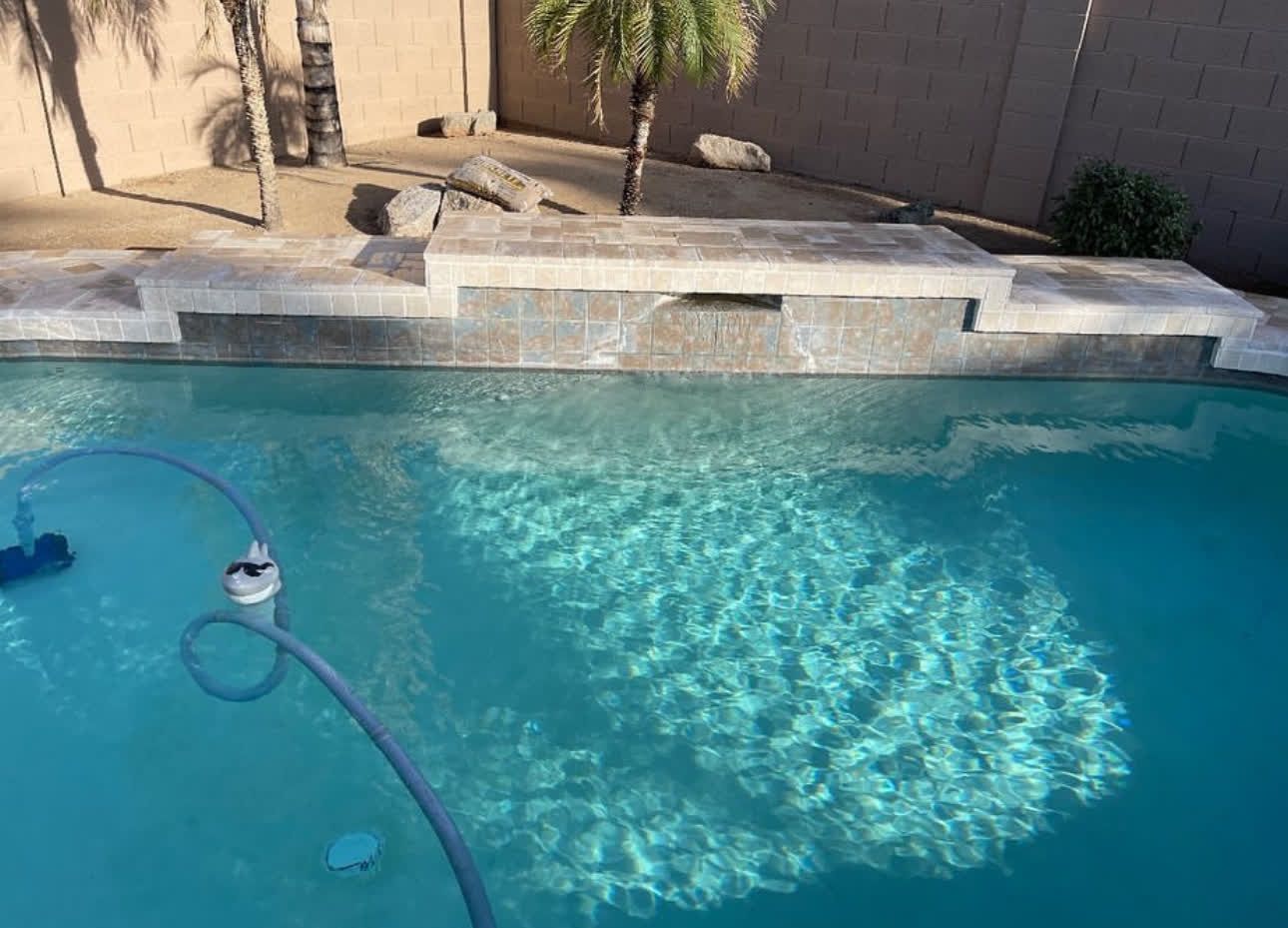 A swimming pool with a vacuum cleaner attached to the side of it.