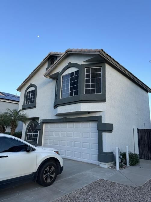 A white car is parked in front of a white house