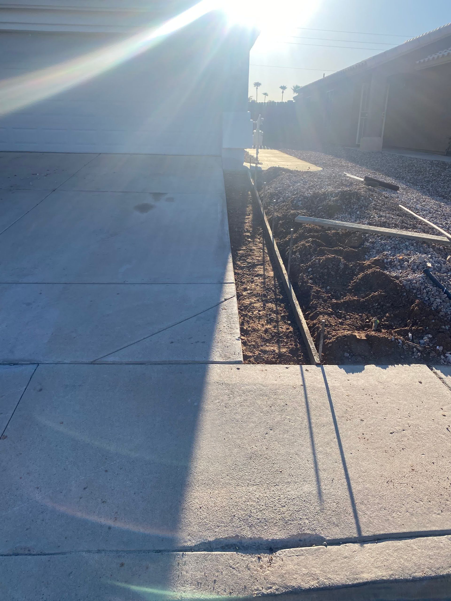A shadow of a person is cast on a sidewalk in front of a house.