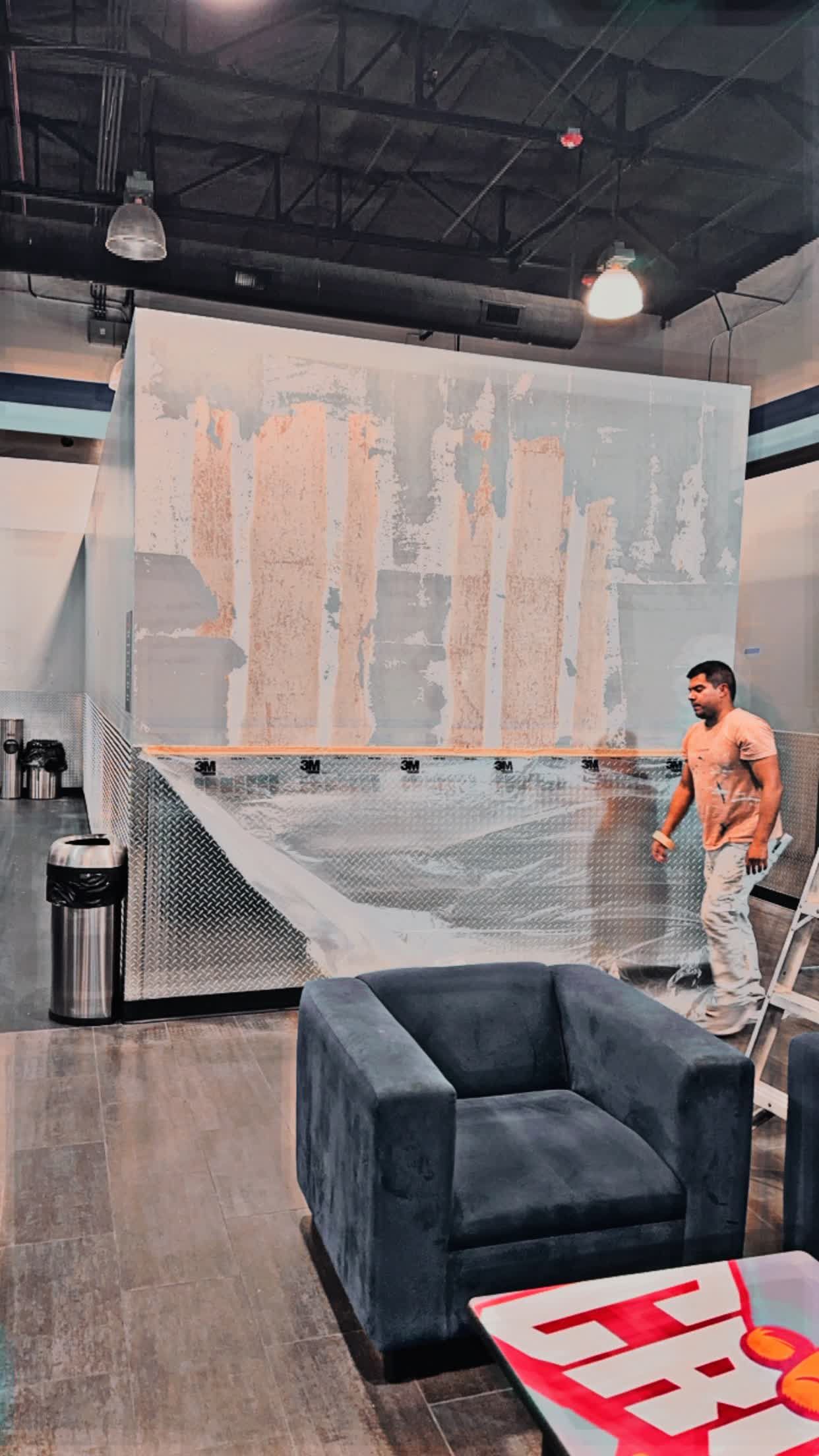 A man is standing in a room with a chair and a table.