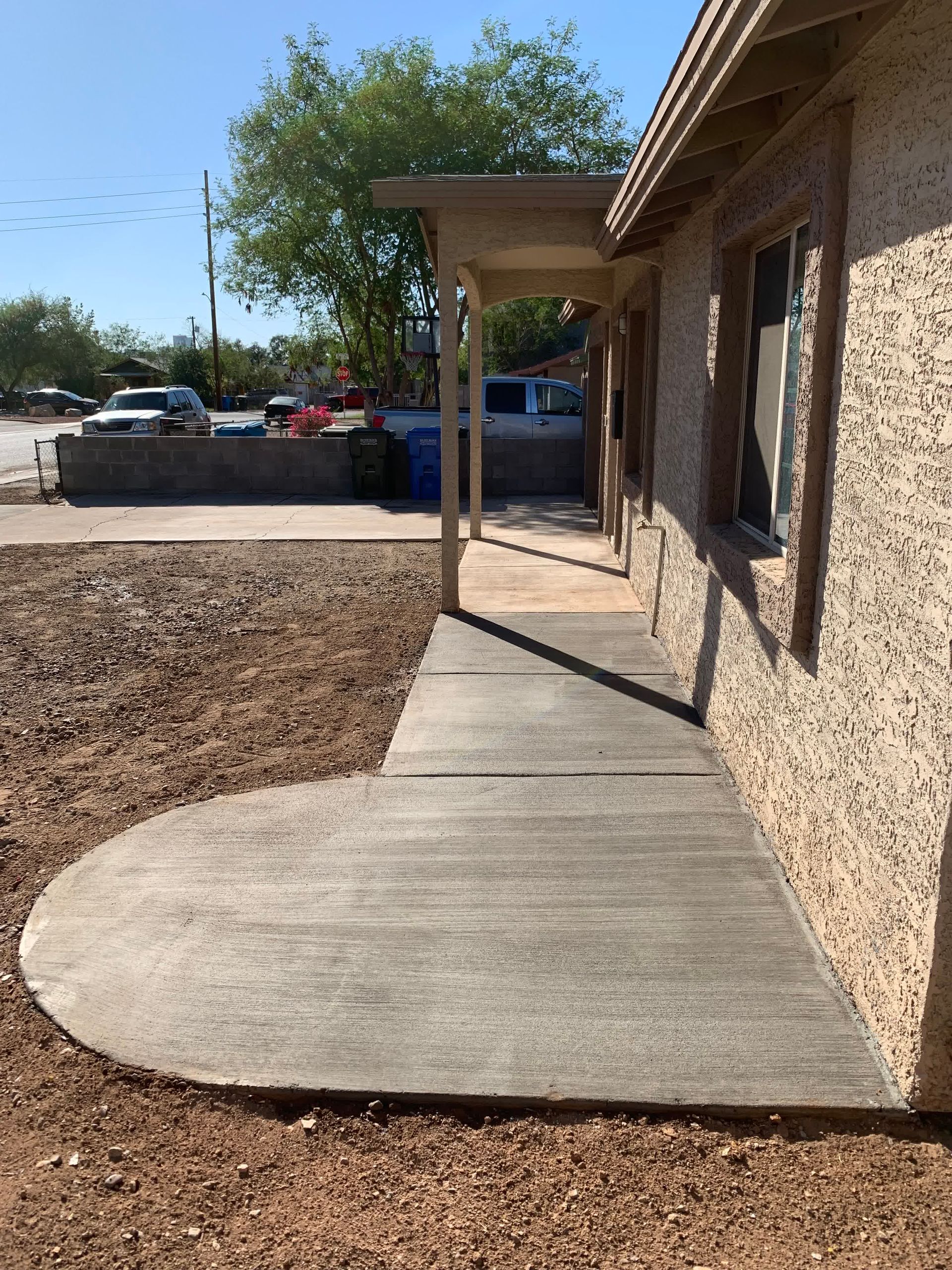 A concrete walkway leading to a house with a porch