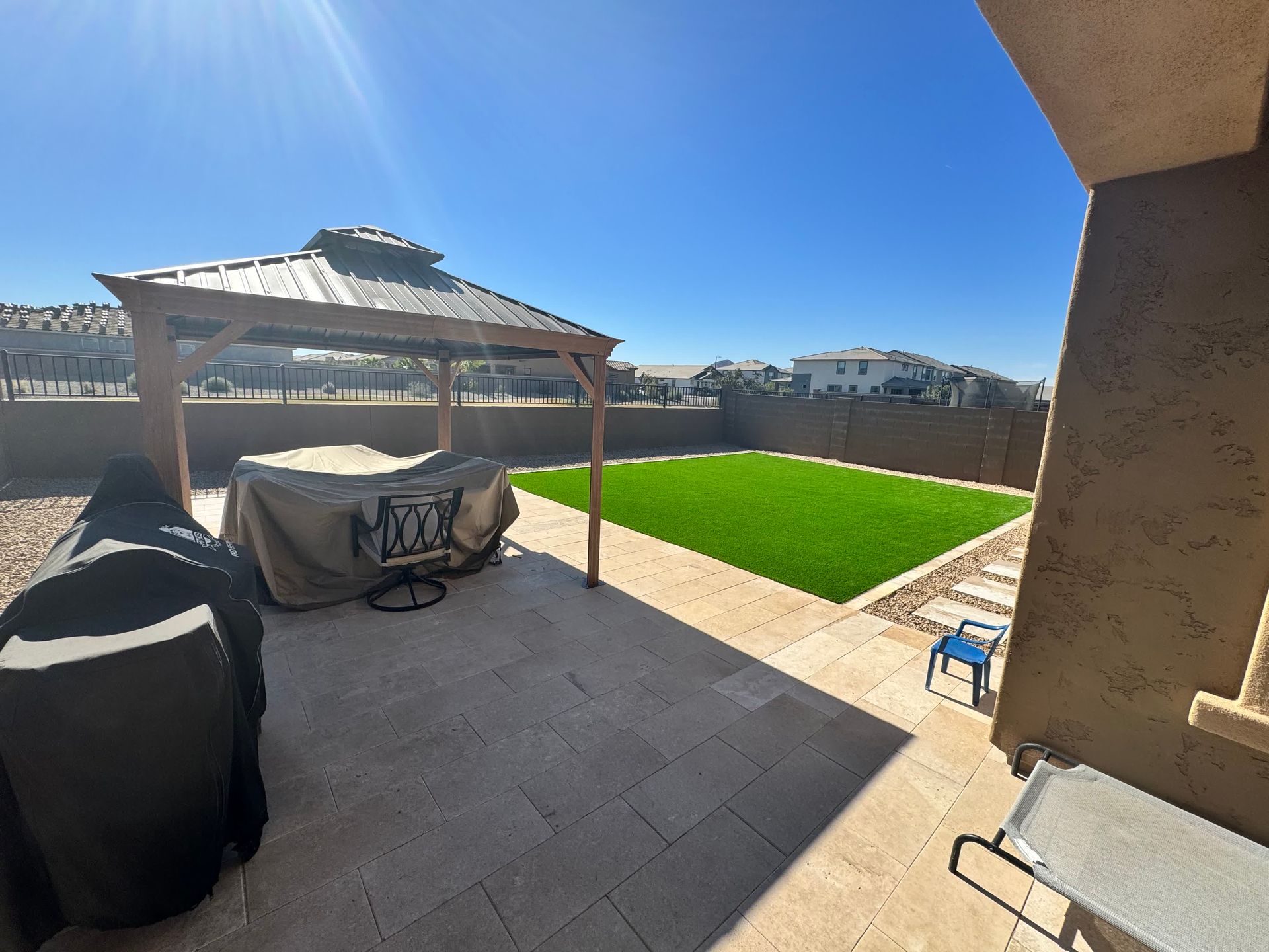 A backyard with a gazebo and a table with a cover on it