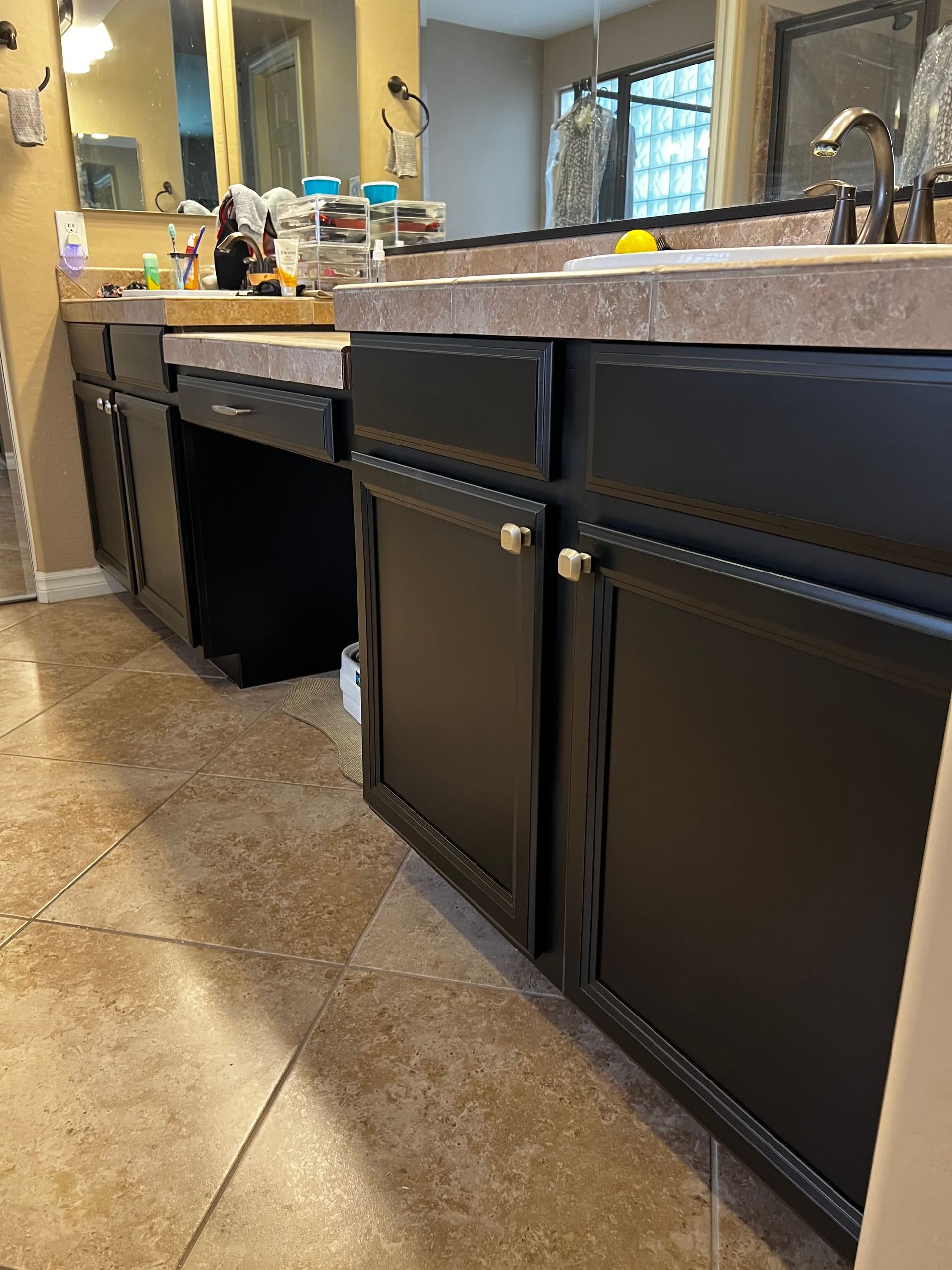 A bathroom with black cabinets , a sink , and a mirror.