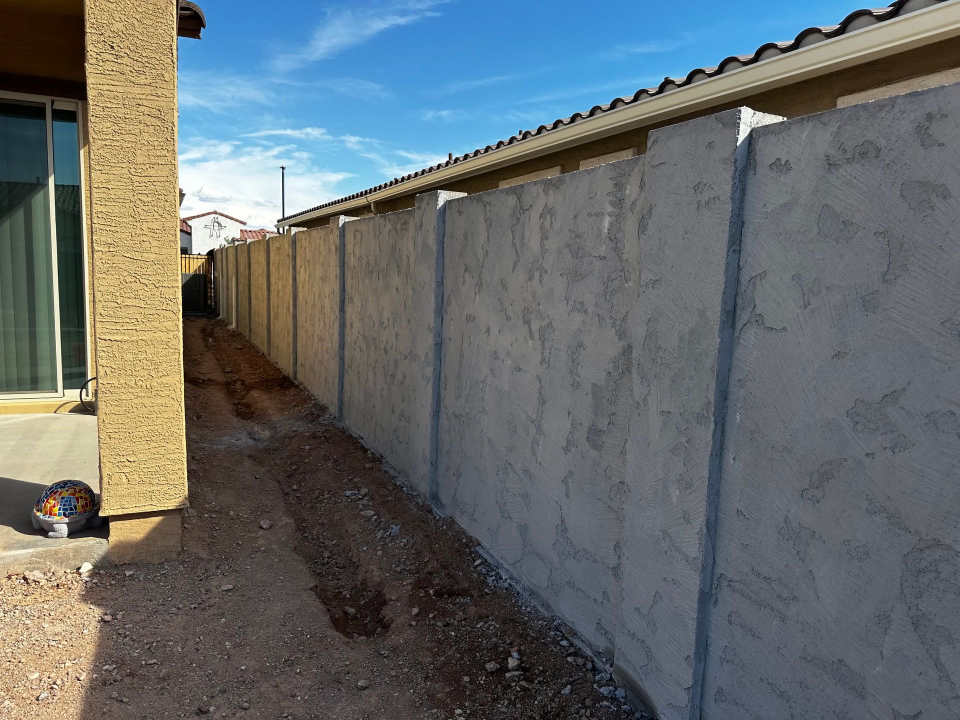 A concrete fence is being built in the backyard of a house.