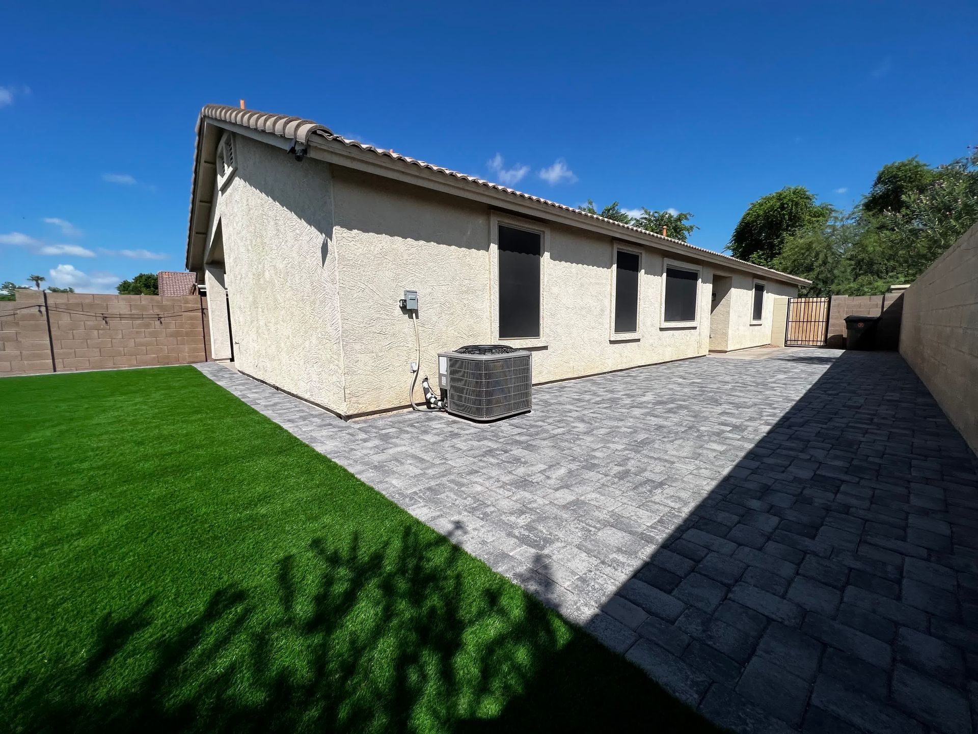 The backyard of a house with a patio and lawn.