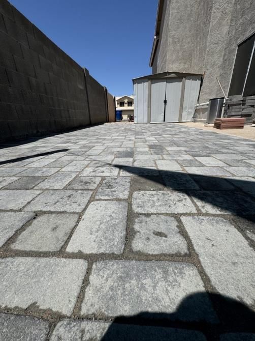 A brick driveway with a shed in the background