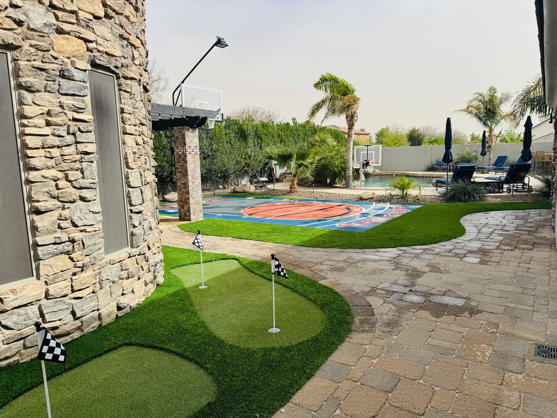 There is a putting green in the backyard of a house.