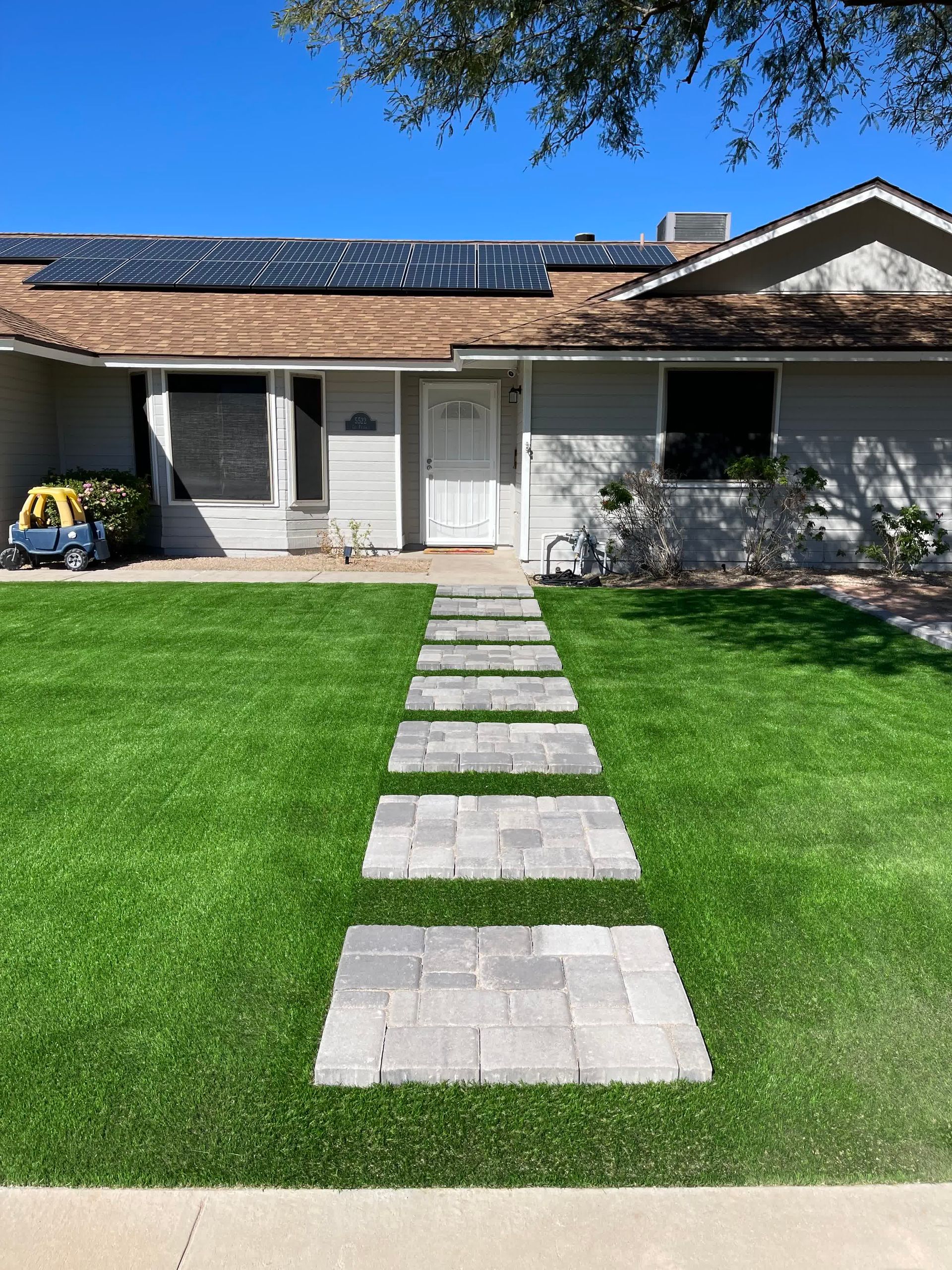 A house with a lush green lawn and a walkway leading to it.