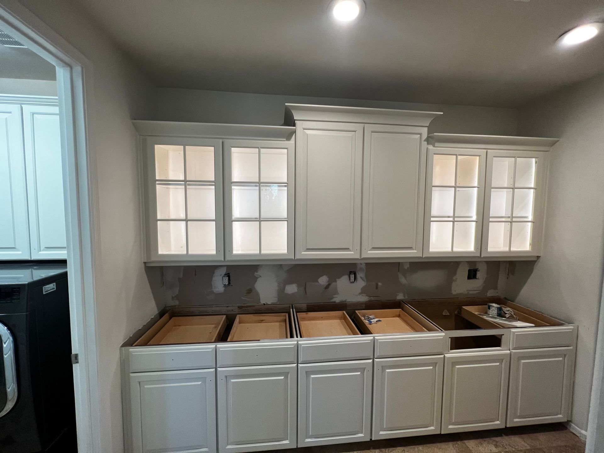A kitchen with white cabinets and a washer and dryer in the background.