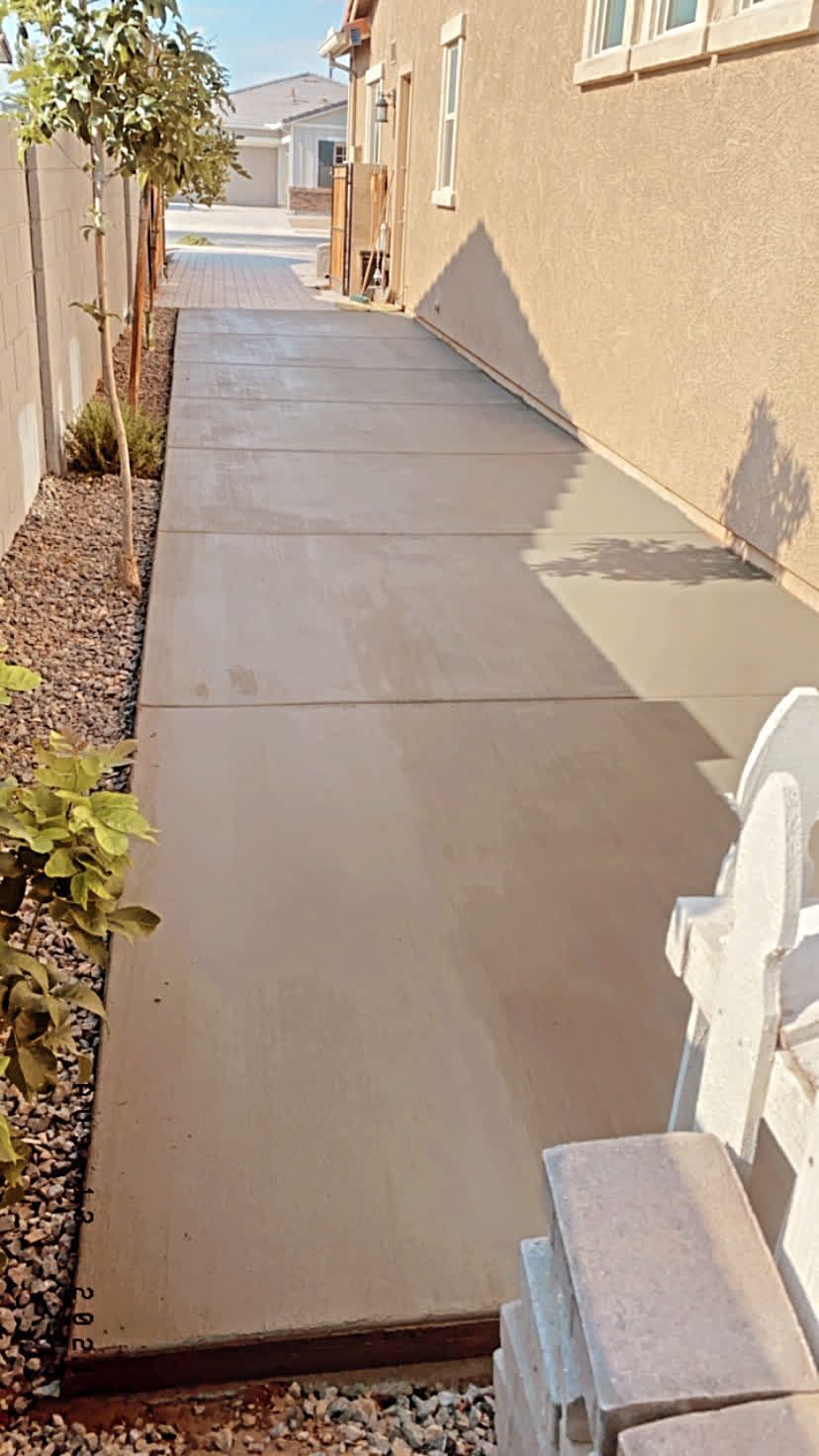 A concrete walkway leading to the side of a house.