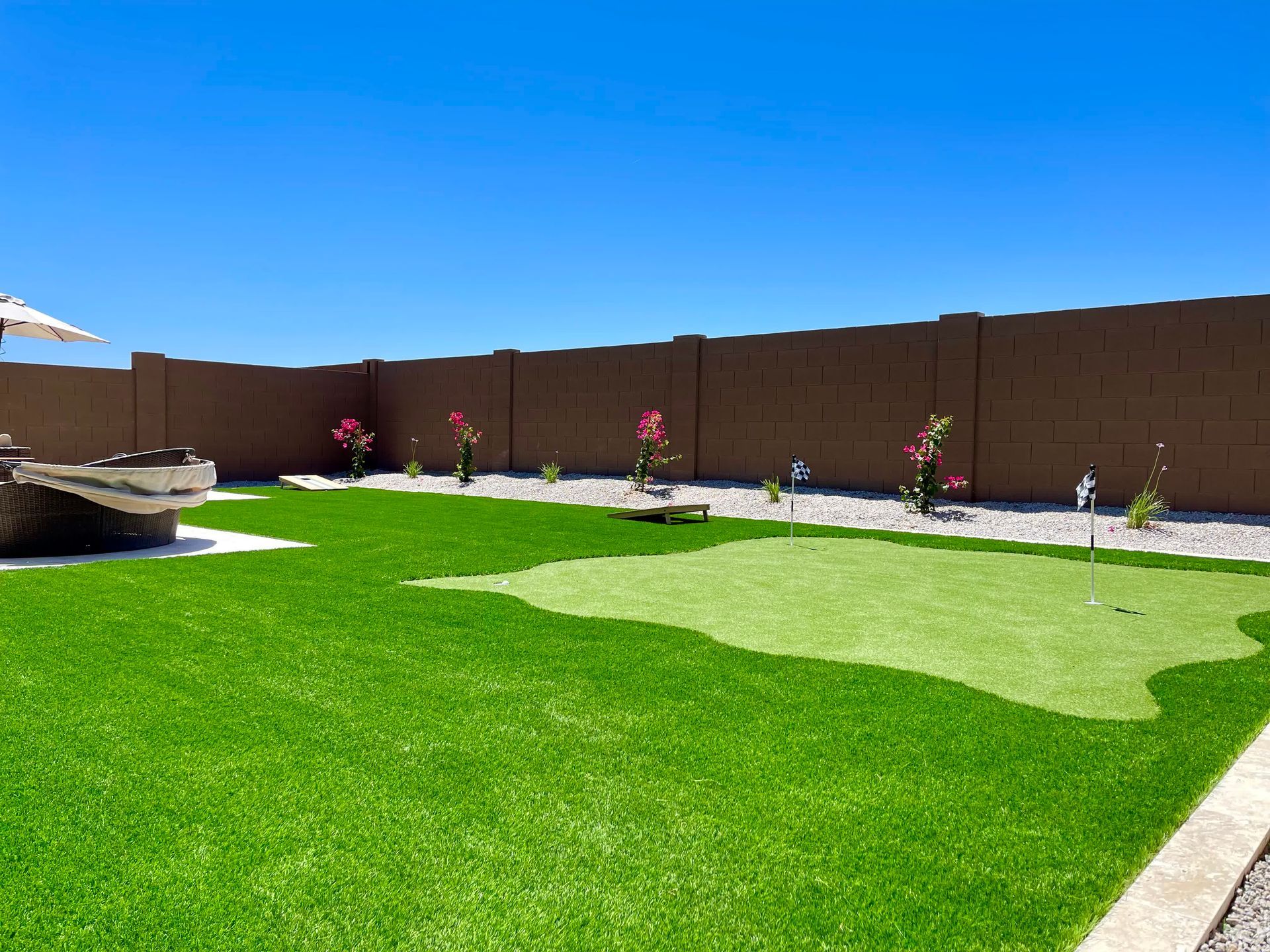 A backyard with a putting green and a fence.