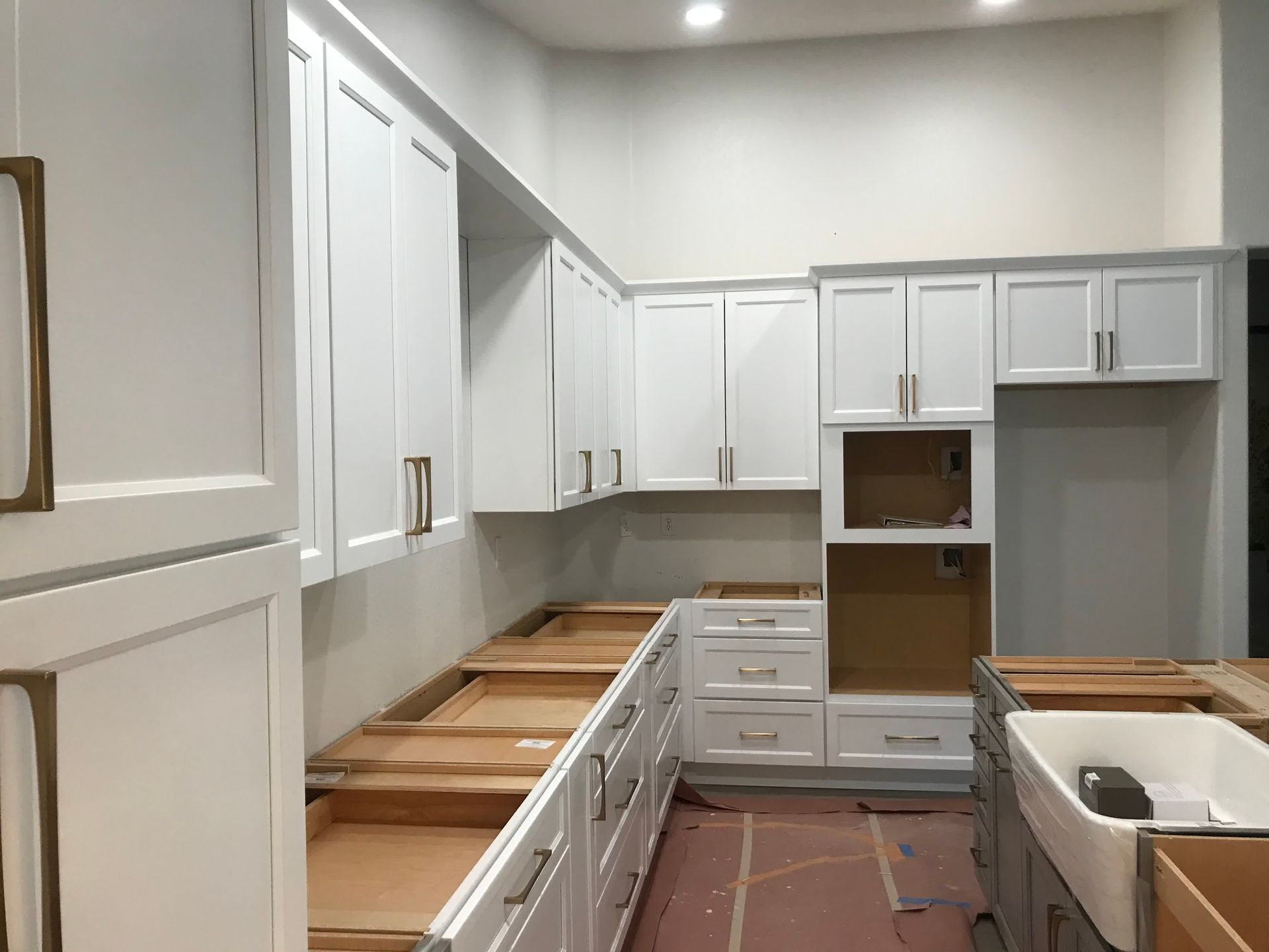 A kitchen under construction with white cabinets and a sink.
