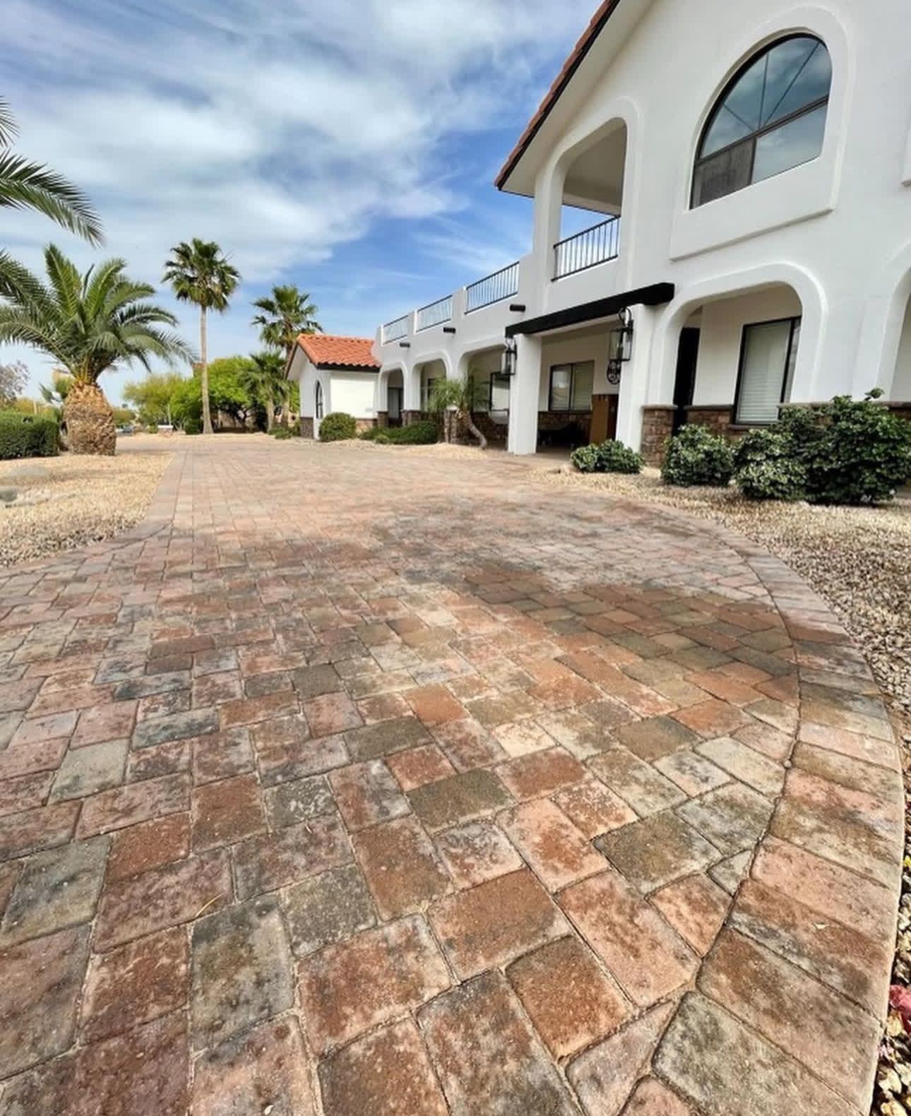 A large white house with a brick driveway in front of it