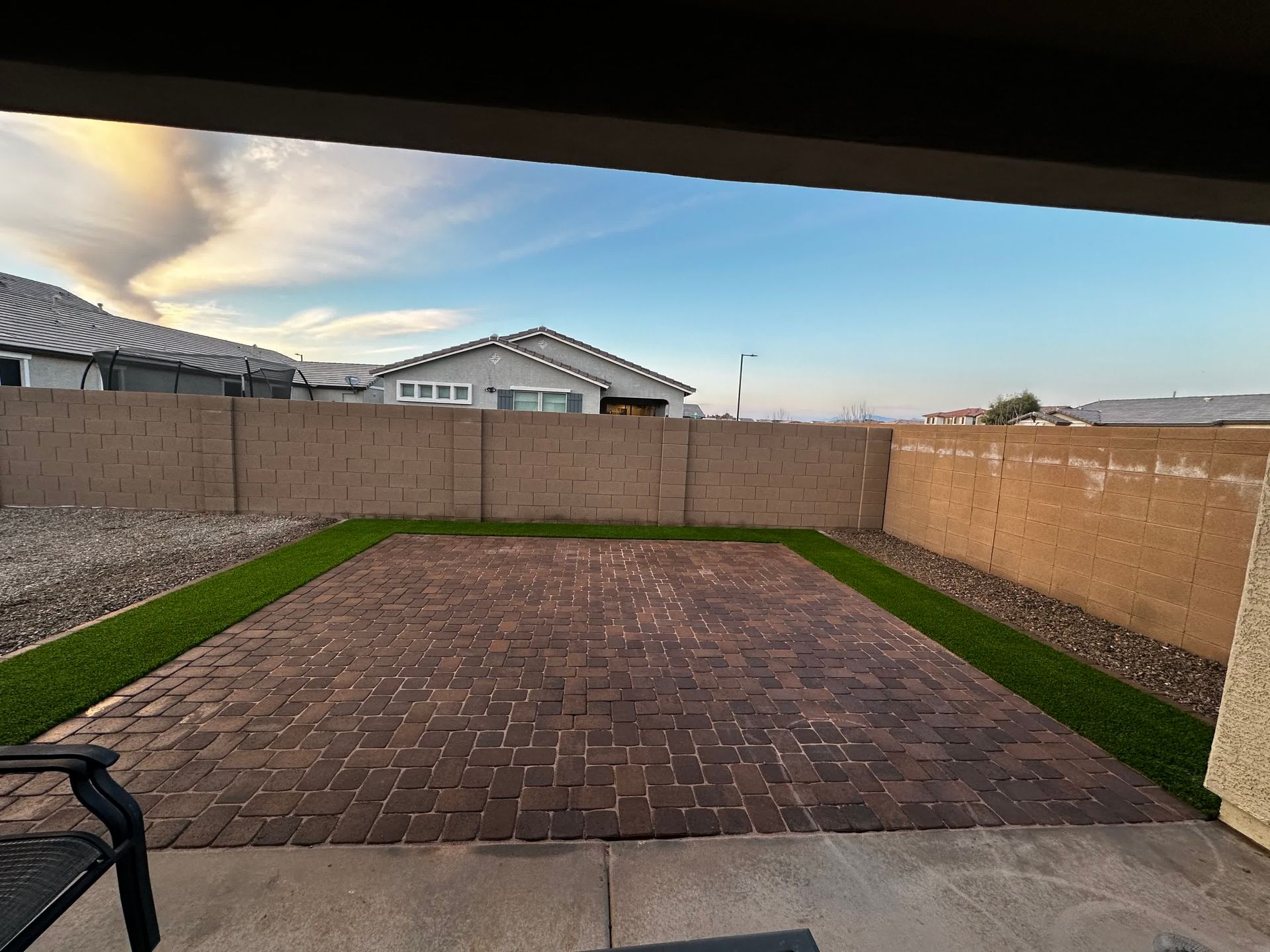 A backyard with a brick walkway and a fence
