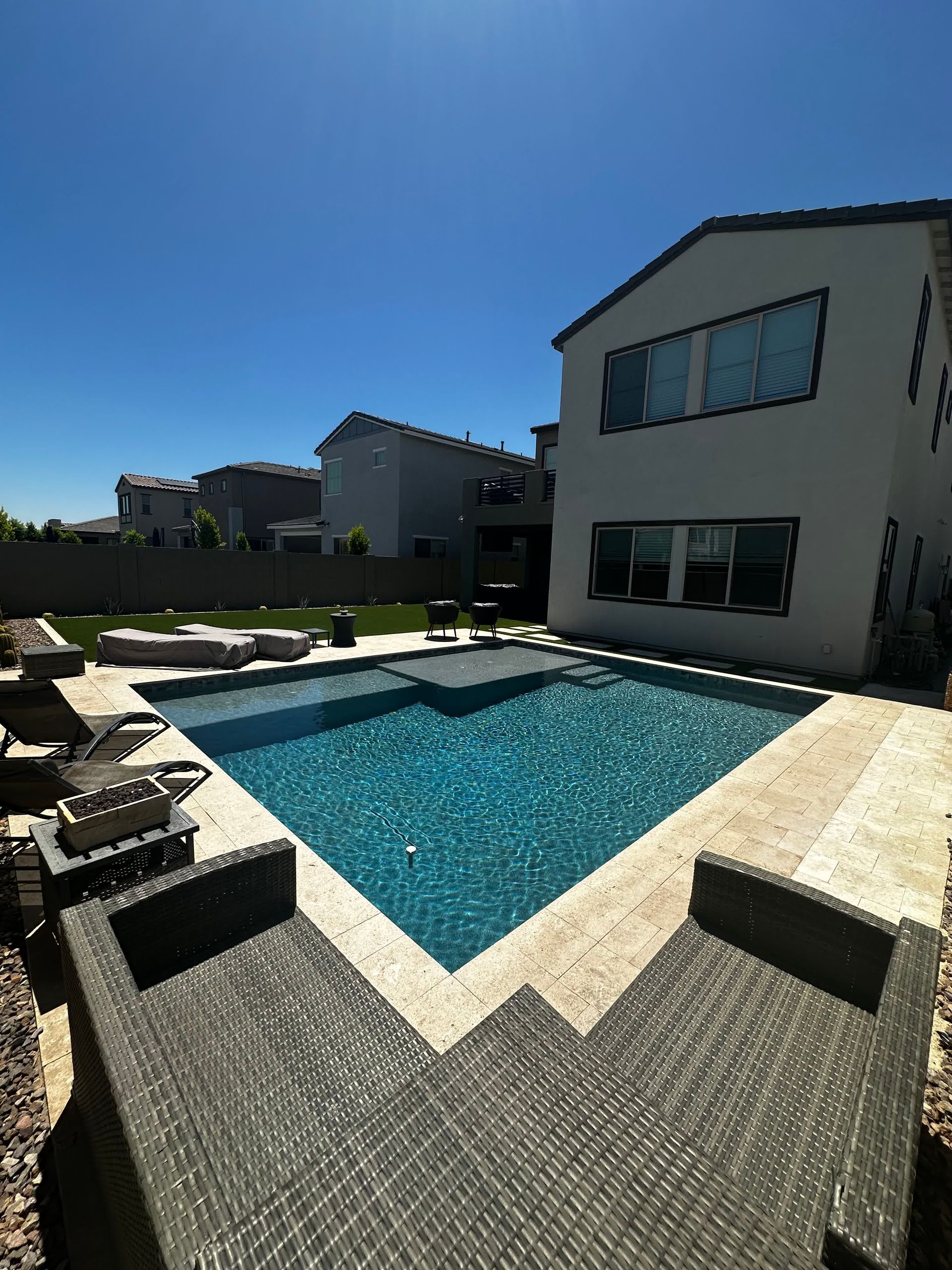 A large swimming pool is in the backyard of a house.