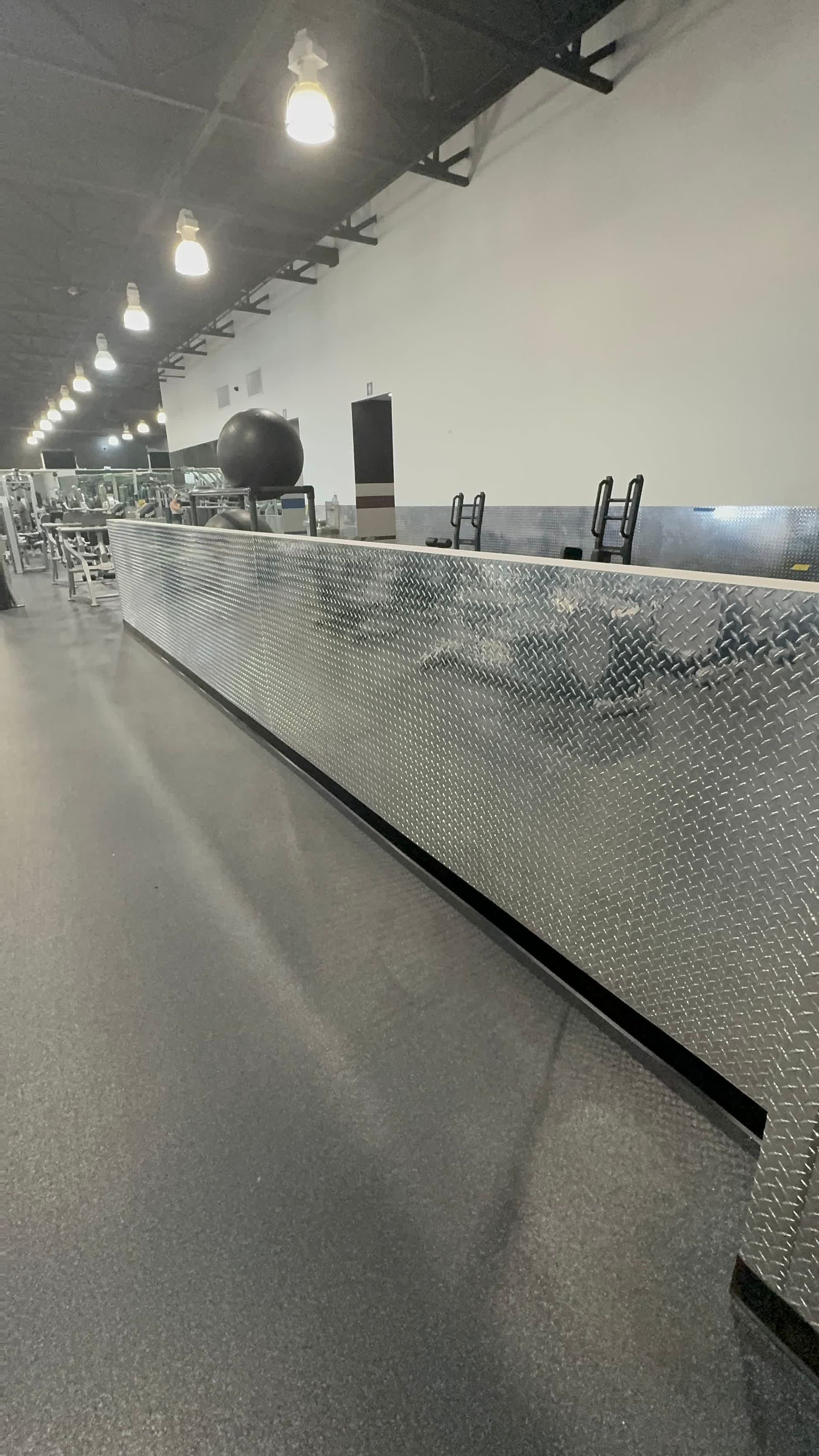 A long hallway in a gym with a lot of equipment wrapped in plastic.