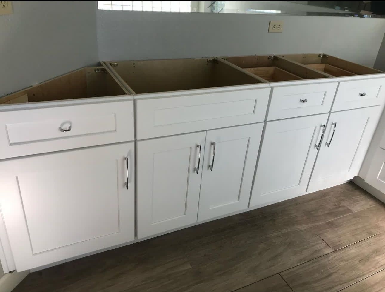 A kitchen with white cabinets and drawers and a sink.