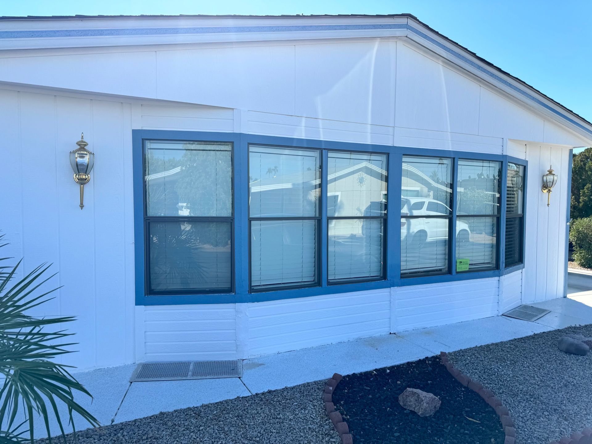 A white mobile home with blue trim and windows.