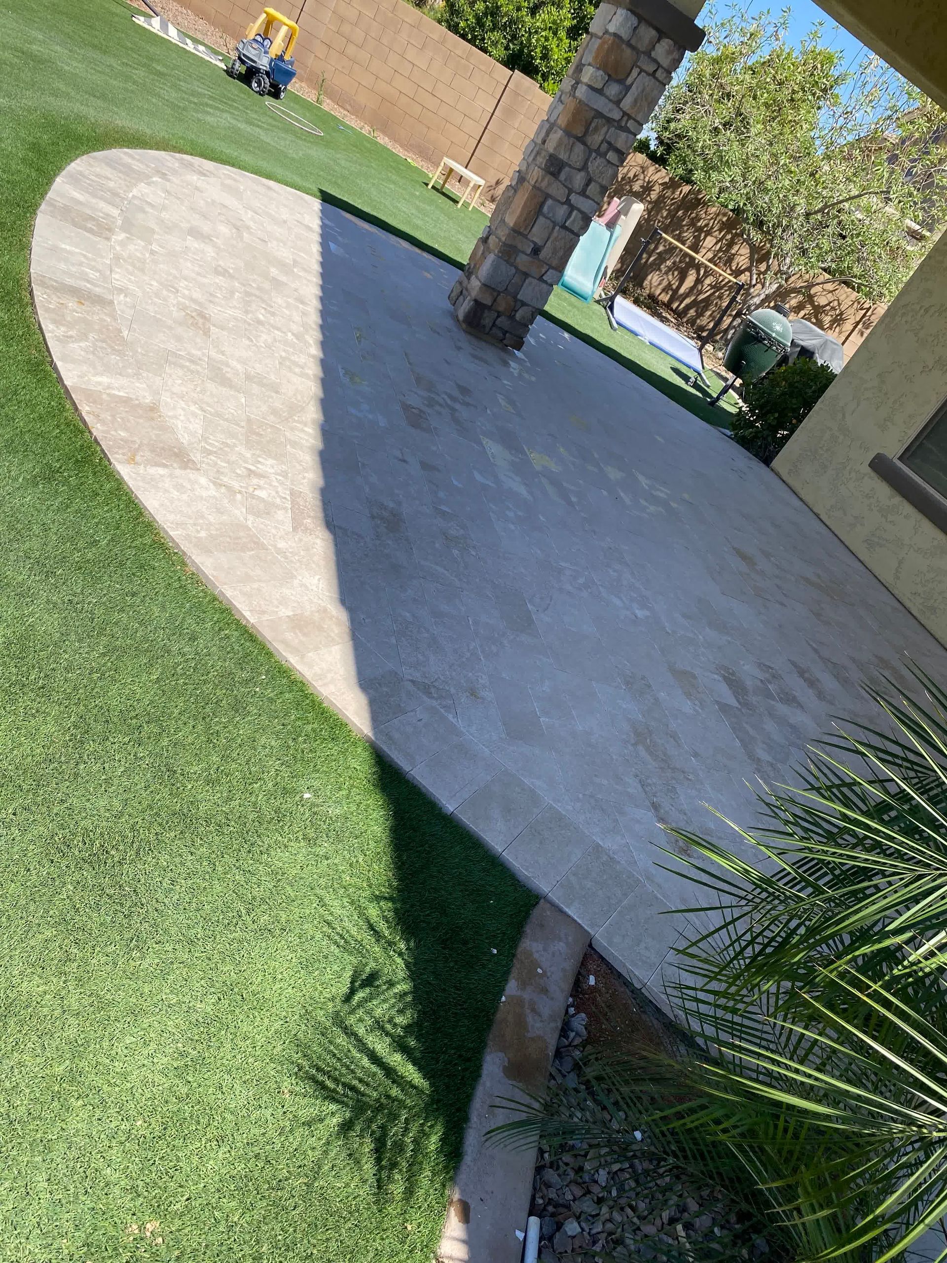 A patio with a shadow of a person on it in a backyard.