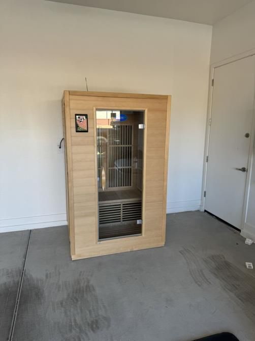 A wooden sauna is sitting in a garage next to a door.