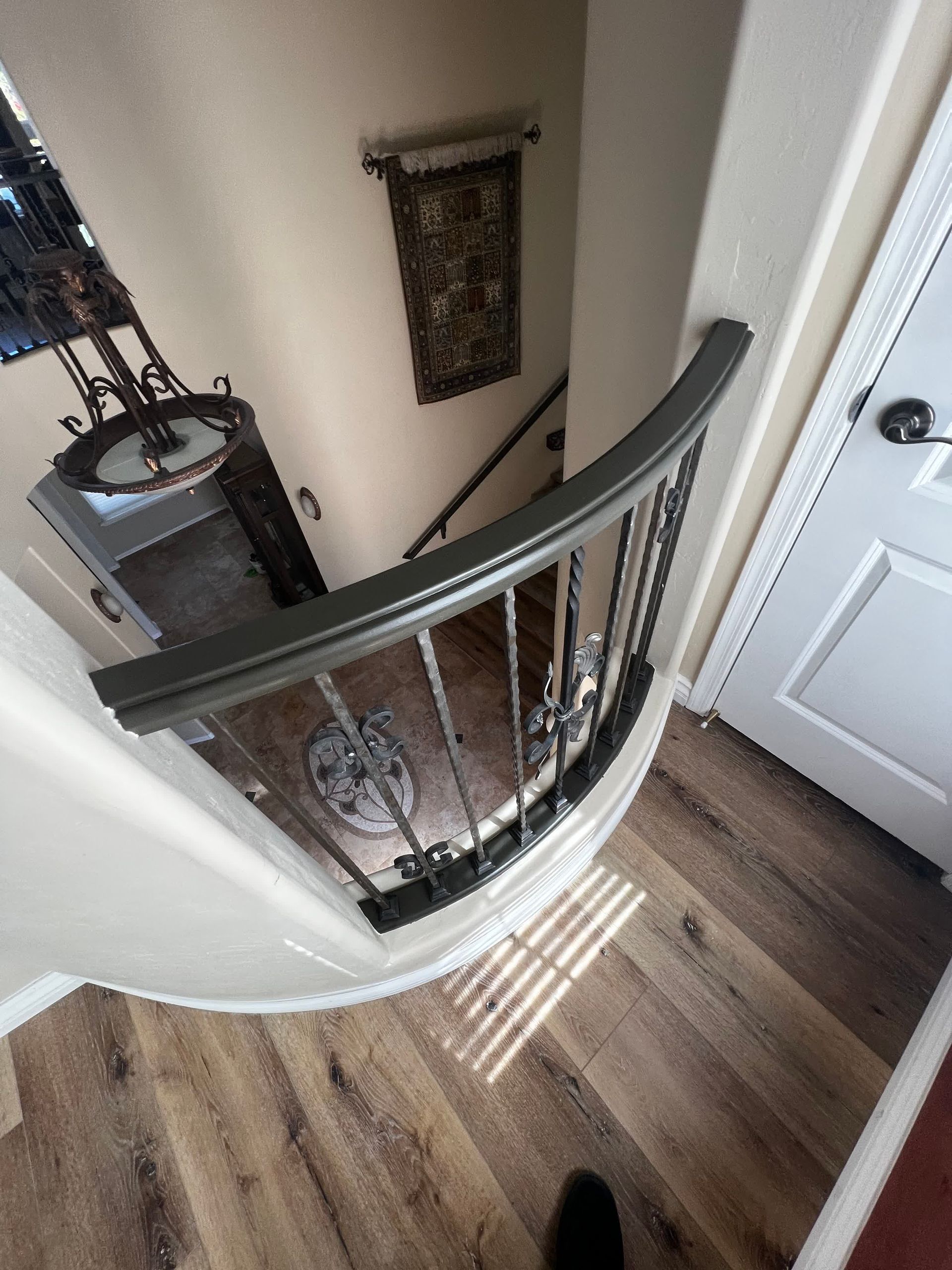 An aerial view of a curved staircase with a wrought iron railing.
