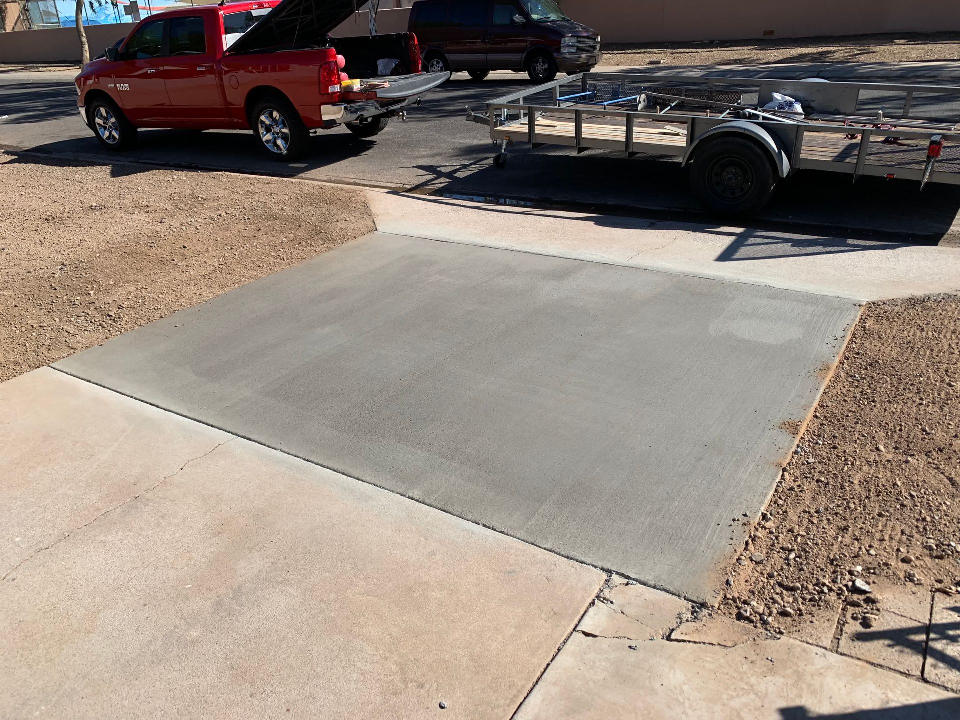 A red truck is parked in a driveway next to a trailer.