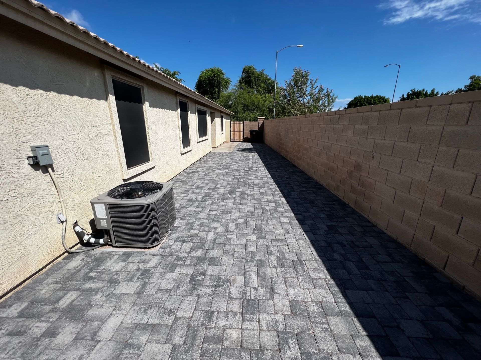 A brick walkway with an air conditioner on the side of a building.