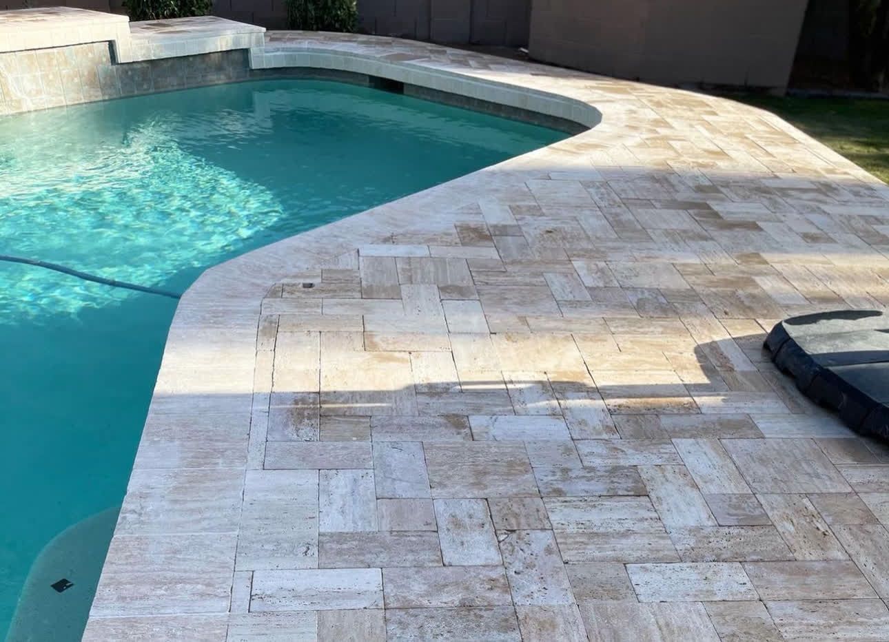 A swimming pool with a tiled deck next to it.