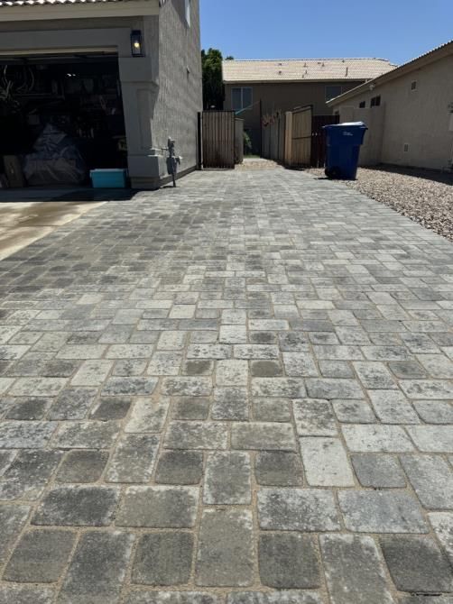 A brick driveway leading to a garage and a house