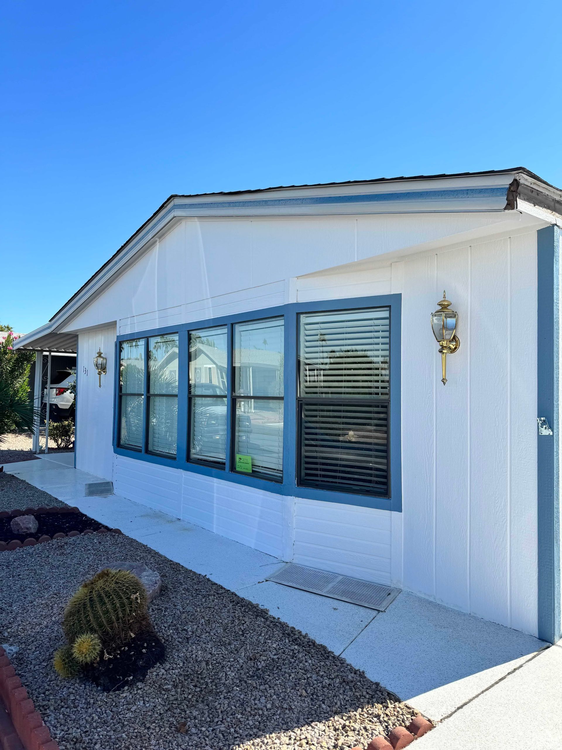 A white mobile home with blue windows and a walkway.