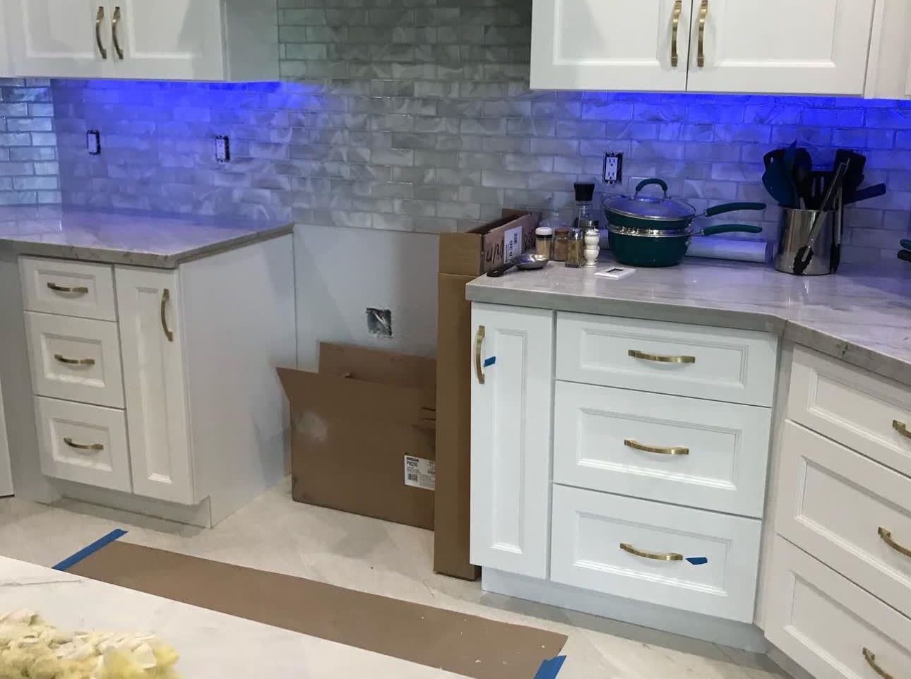 A kitchen with white cabinets and blue lights on the ceiling.
