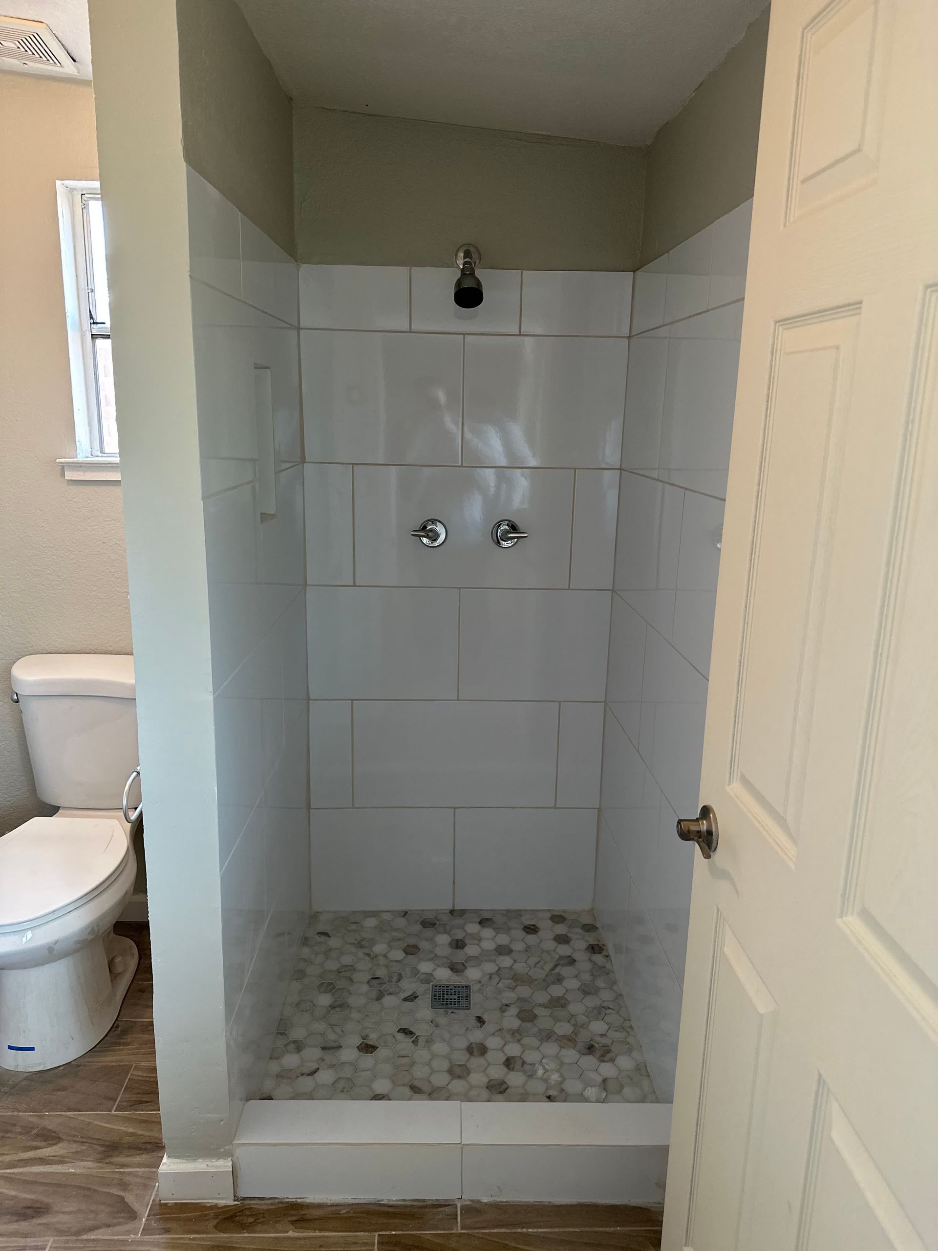 A bathroom with a toilet and a walk in shower.