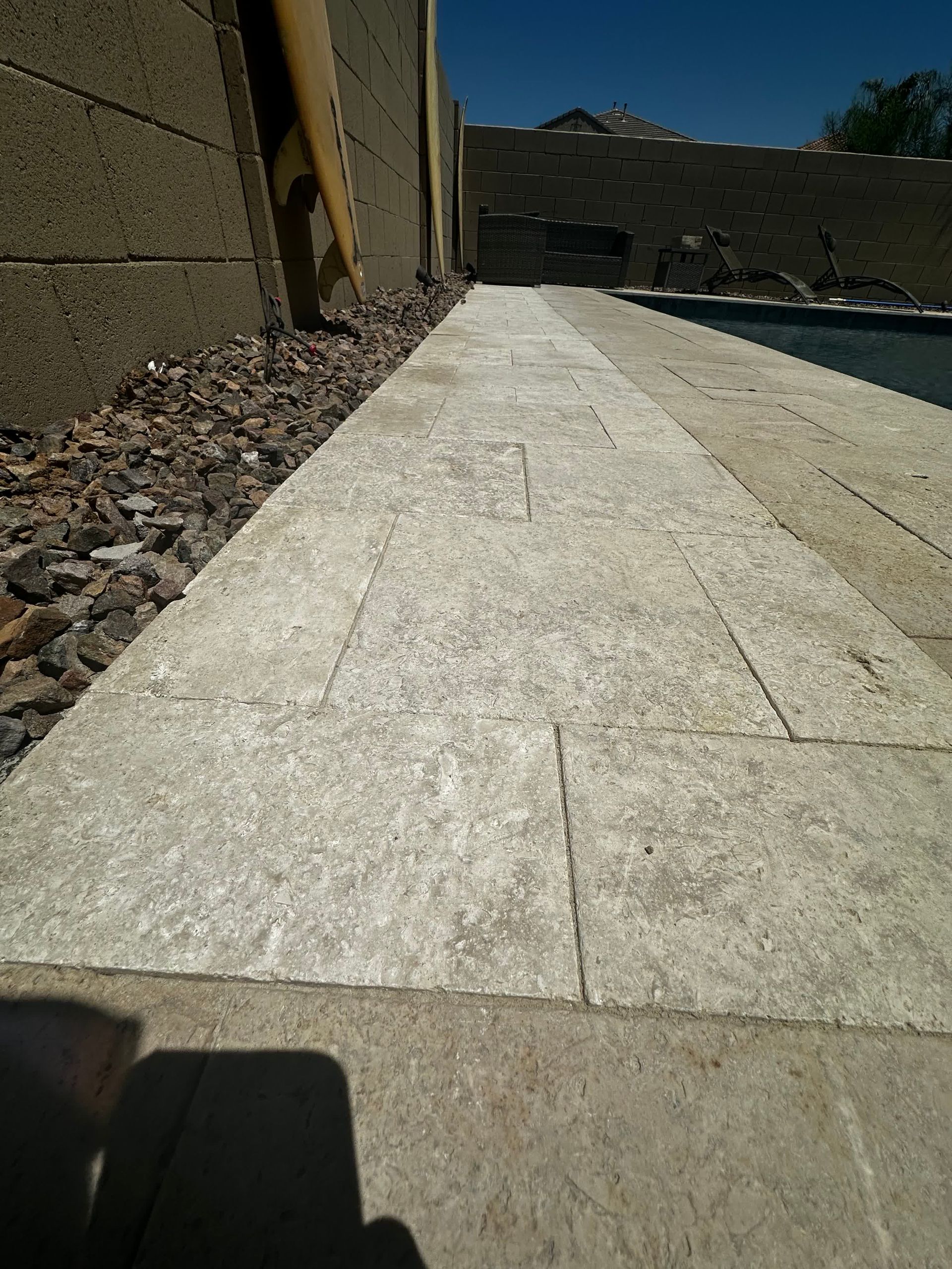A walkway leading to a pool with a brick wall in the background