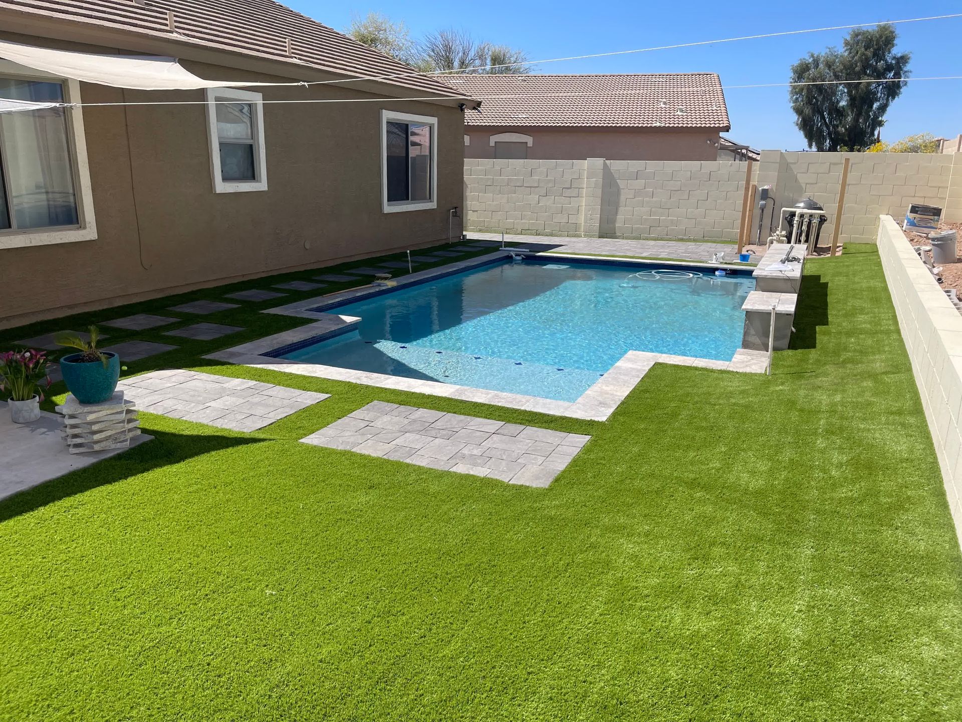 There is a large swimming pool in the backyard of a house.
