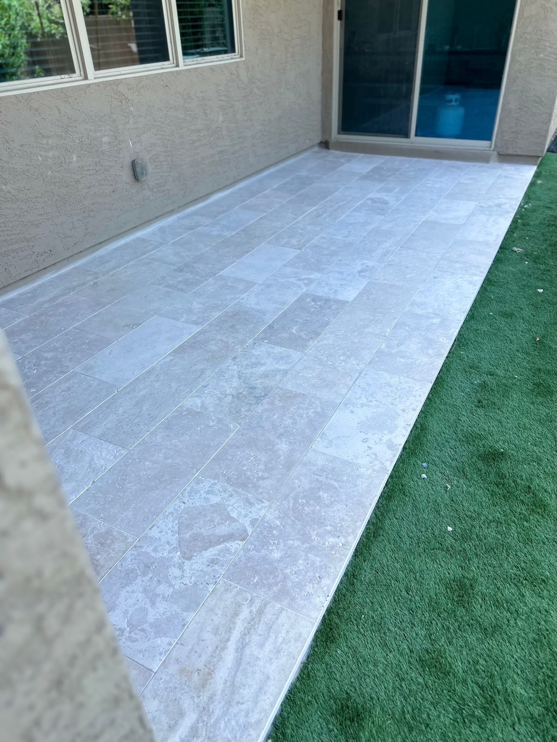 A patio with a sliding glass door and a white tile floor.