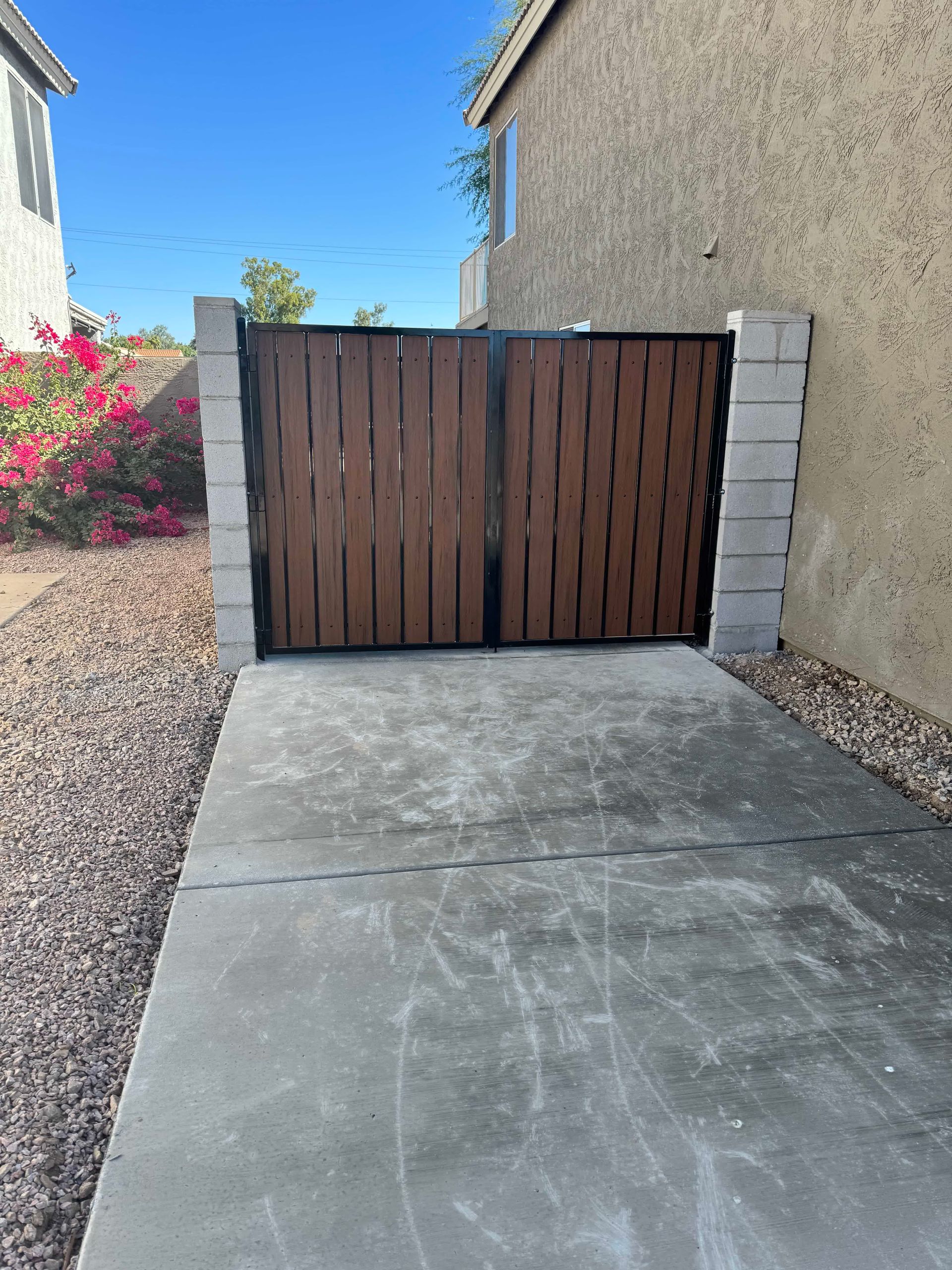 A wooden gate is sitting on the side of a concrete driveway.