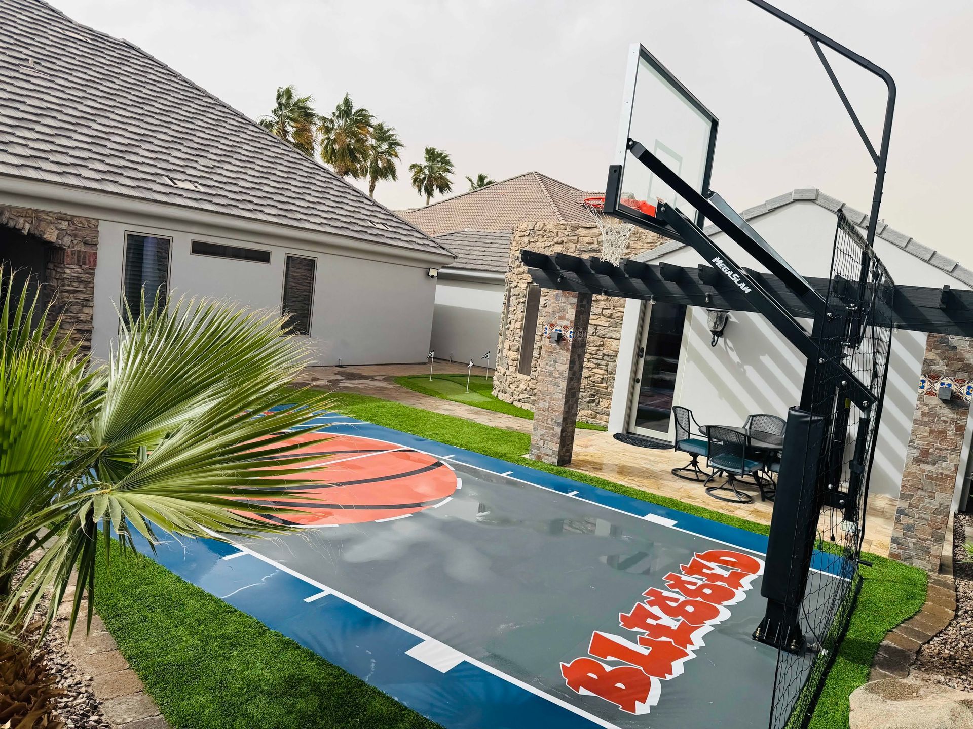 A basketball court is in the backyard of a house.