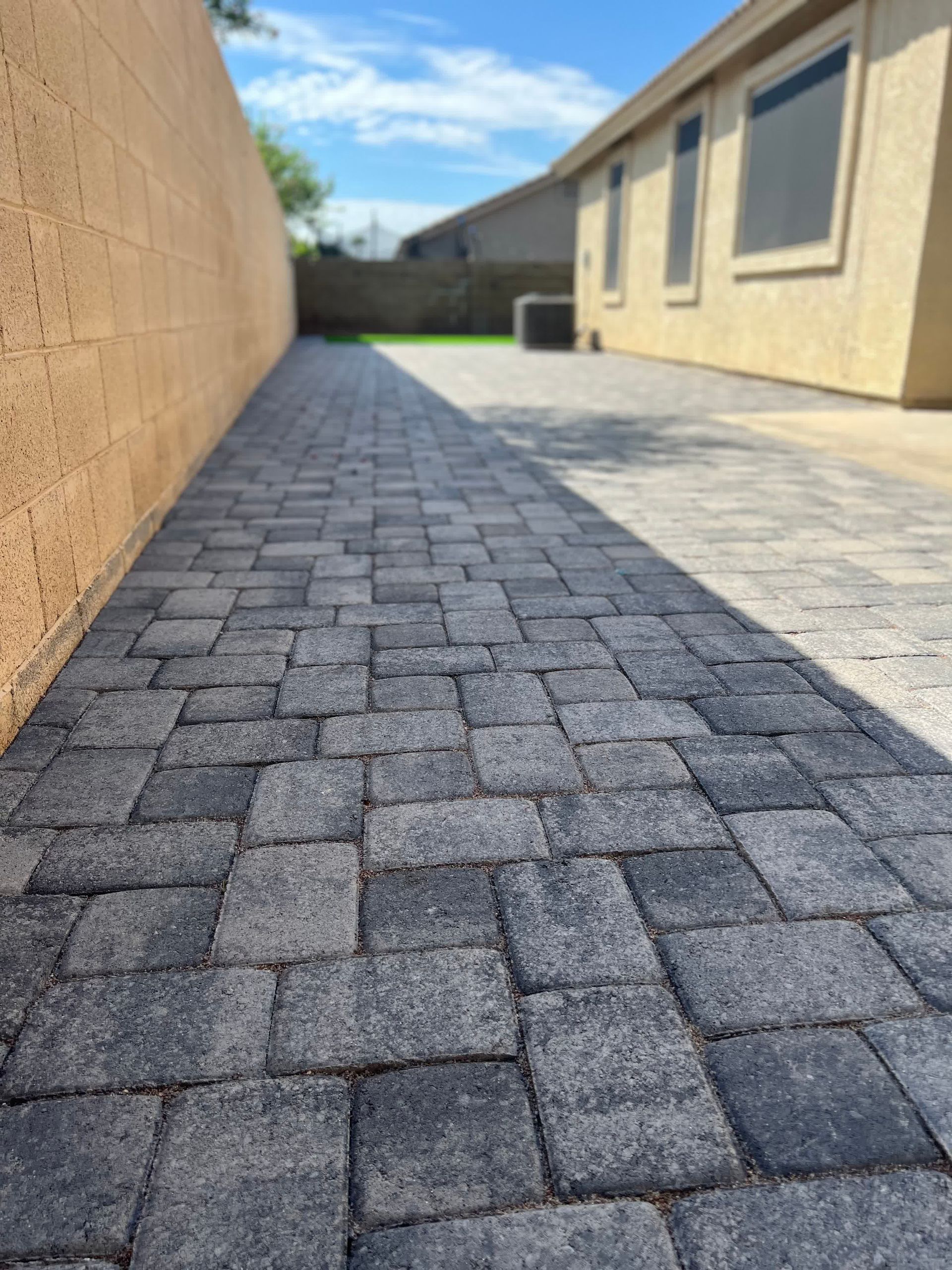 A brick walkway leading to a house on a sunny day